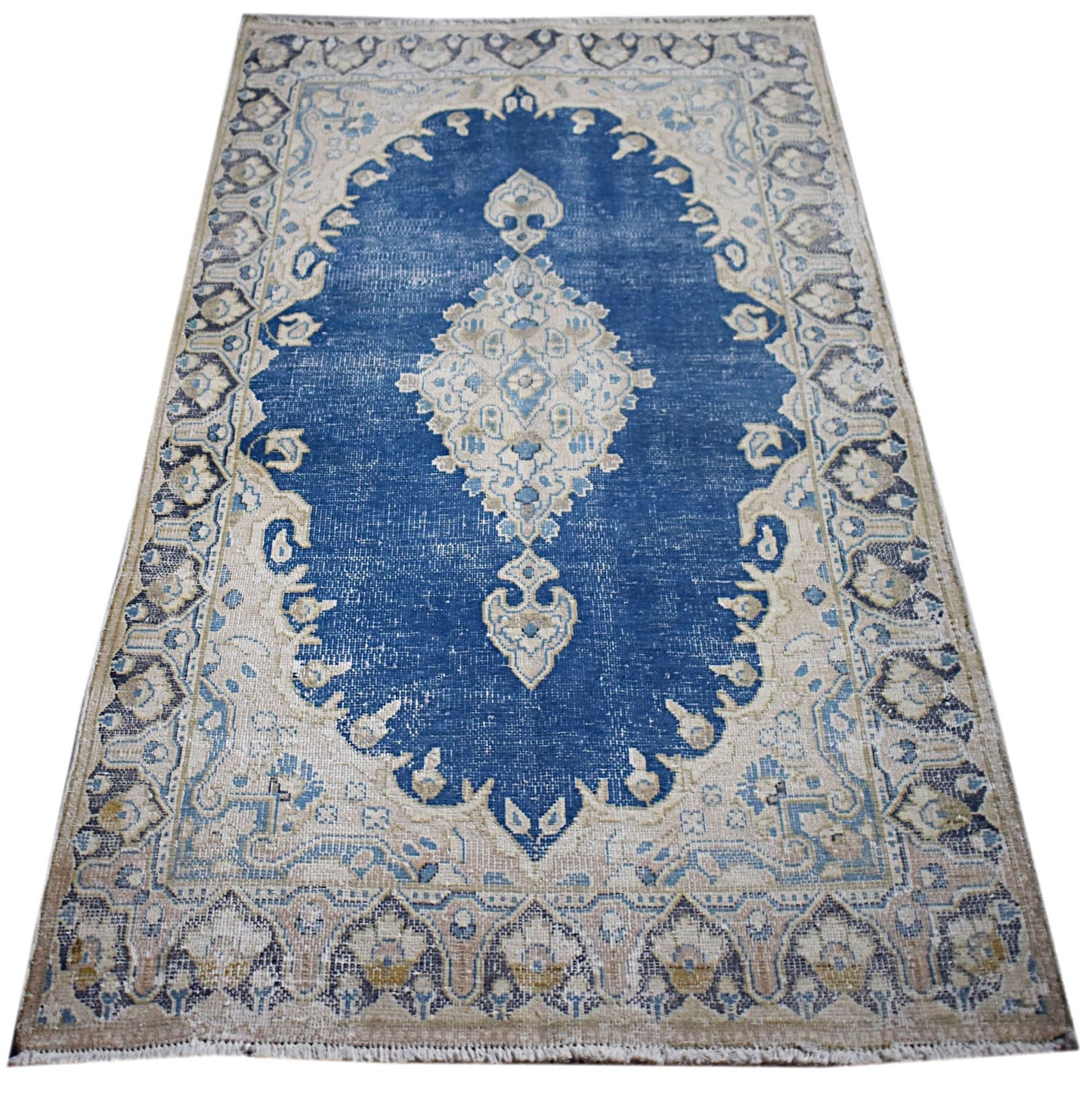 A vintage Persian Kerman rug featuring a central medallion on a blue field with floral borders.