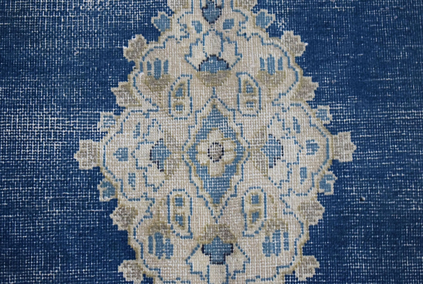 A vintage Persian Kerman rug featuring an intricate central medallion in blue and cream tones.