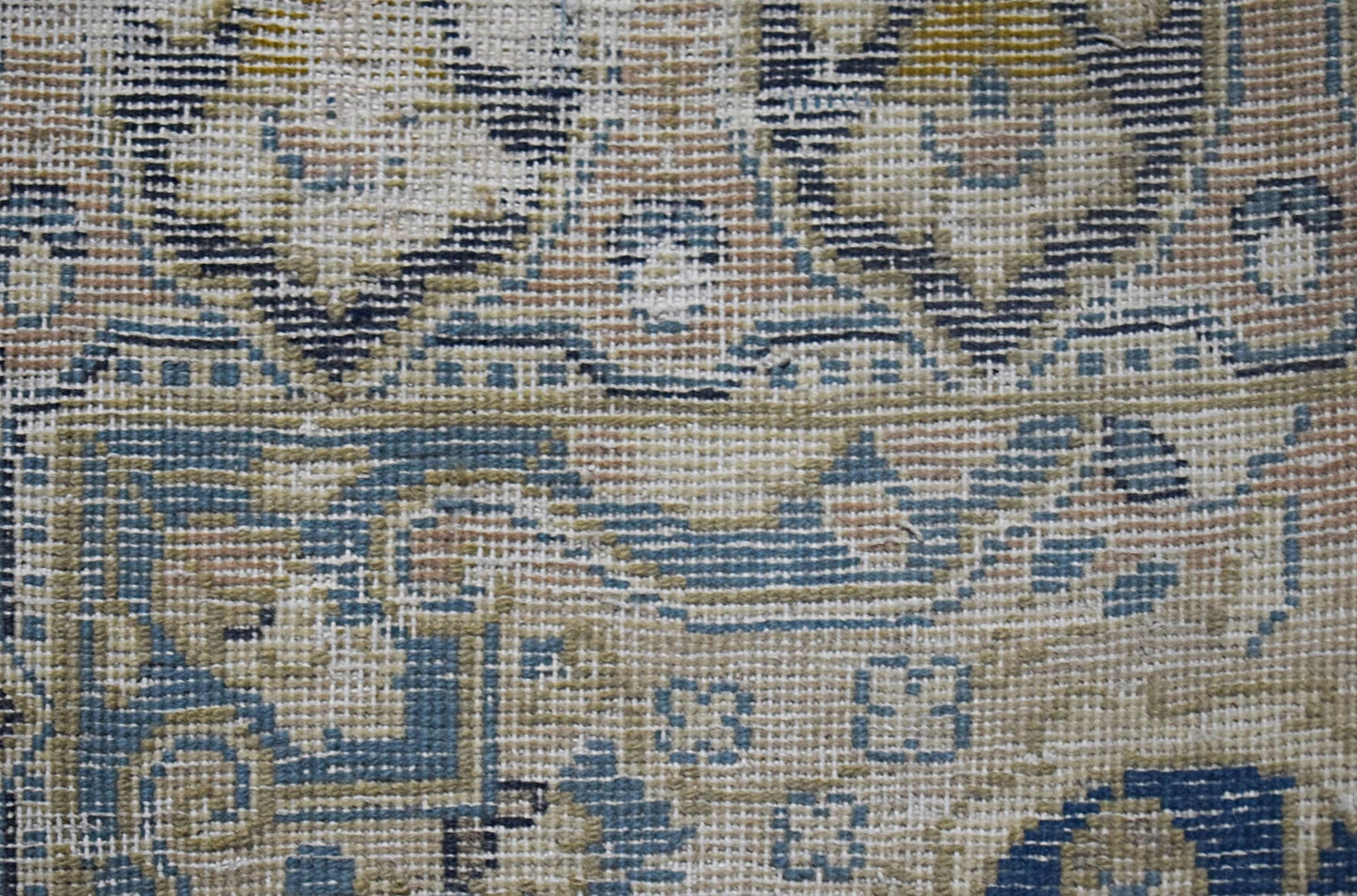 A close-up view of a vintage Persian Kerman rug featuring intricate floral and curvilinear patterns.
