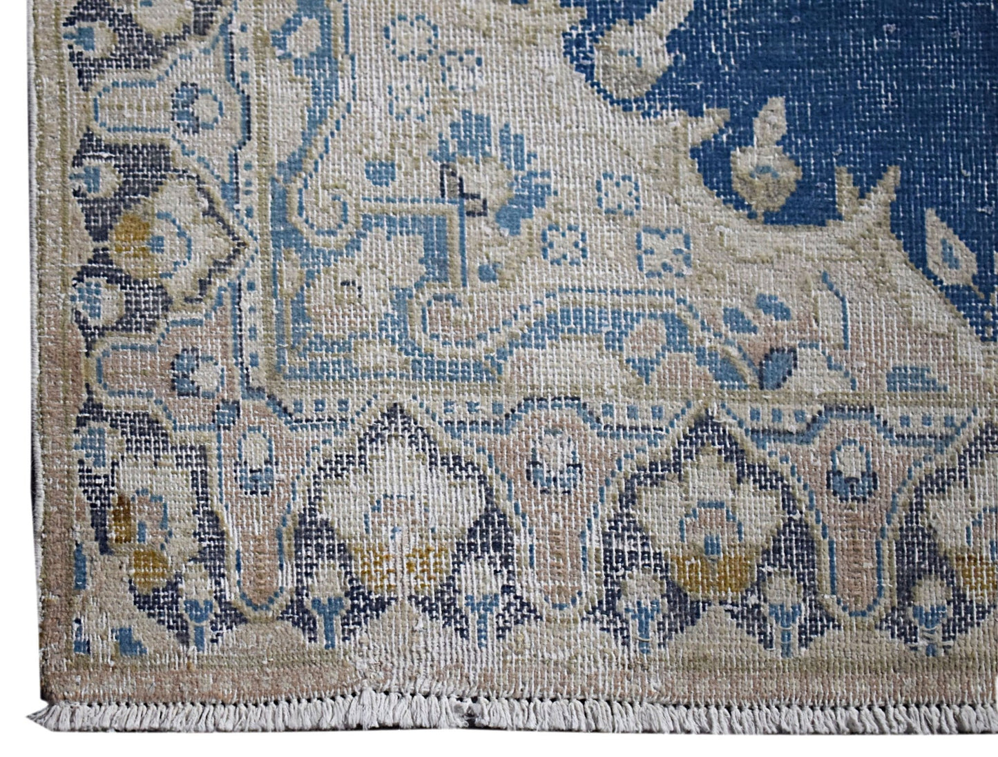 A vintage Persian Kerman rug featuring intricate floral patterns in blue, beige, and cream tones.