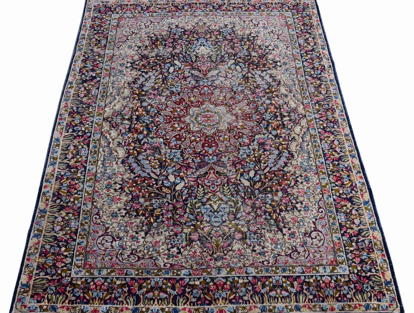 A vintage Persian Kerman rug featuring an intricate floral medallion design in soft, muted tones.