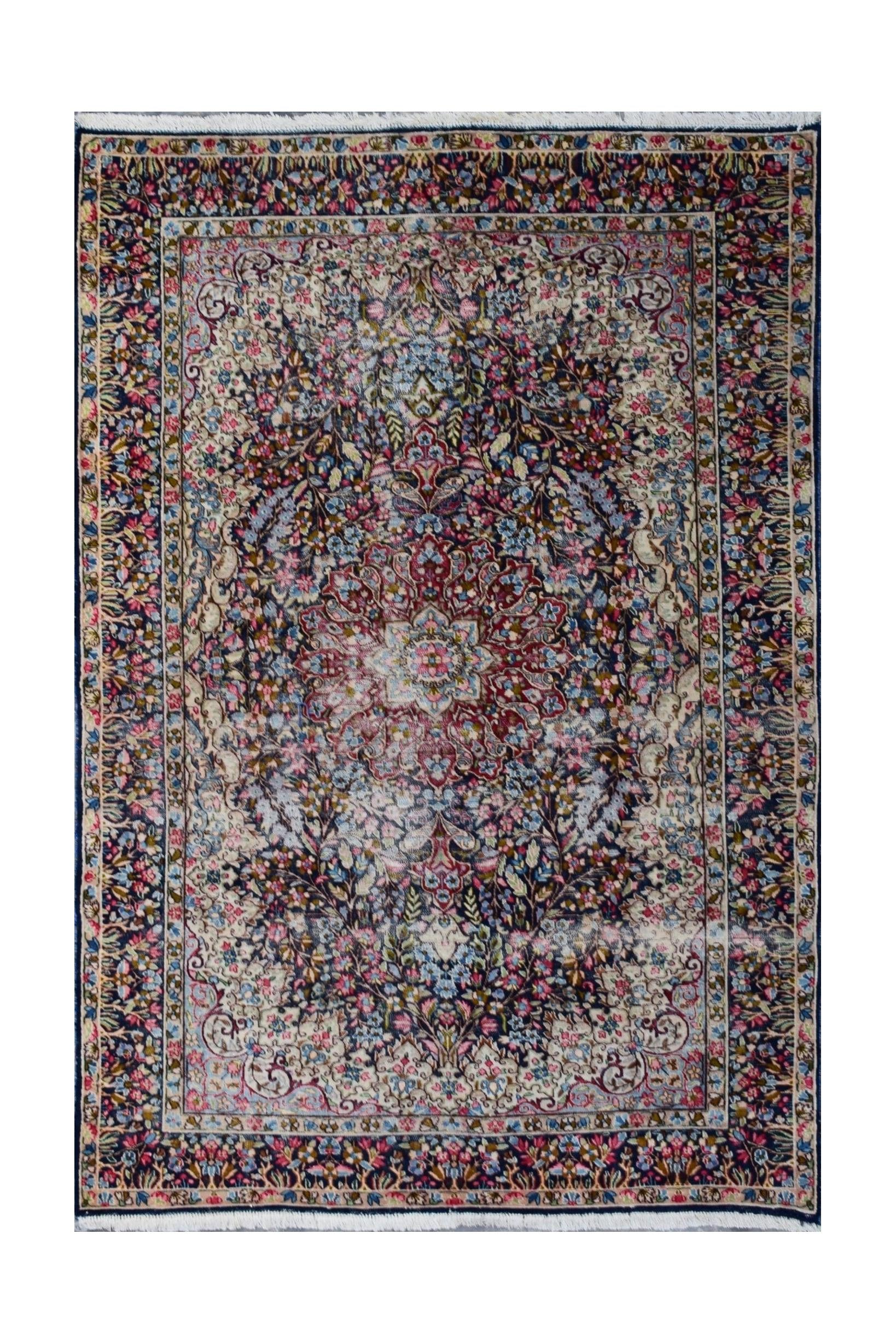 A vintage Persian Kerman rug featuring an intricate floral medallion design in soft, muted tones.