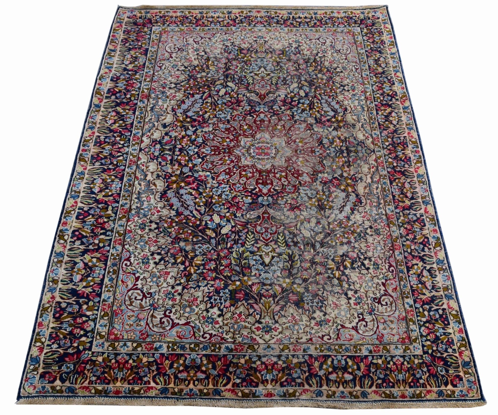 A vintage Persian Kerman rug featuring an intricate floral medallion design in soft, muted tones.