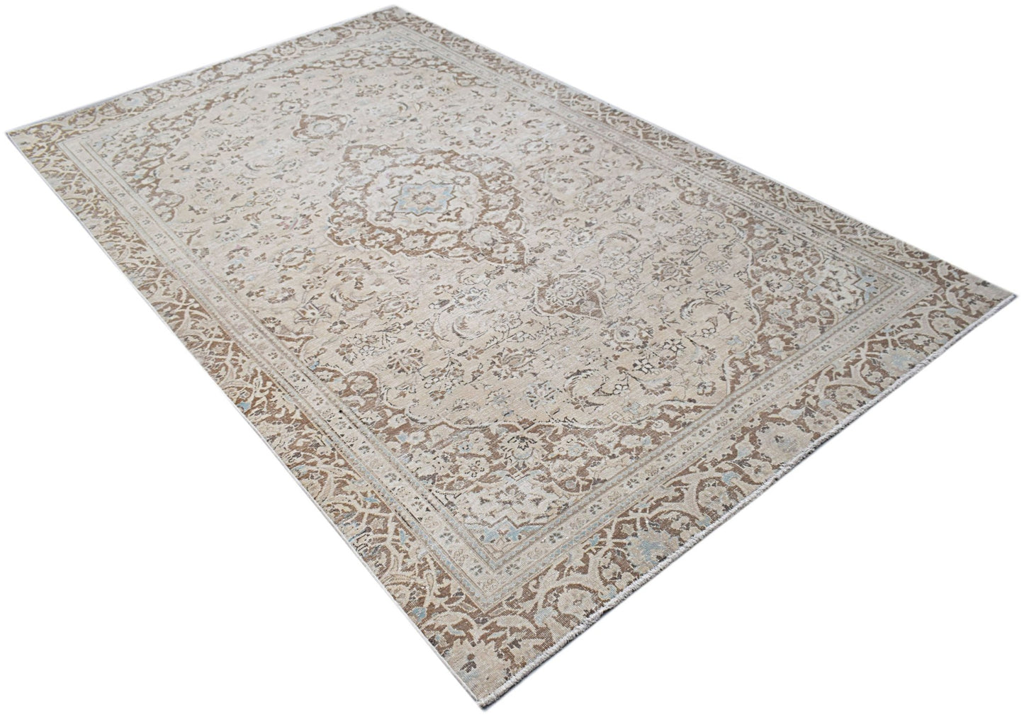 A vintage Persian Kerman rug featuring a central medallion and intricate floral patterns in beige.