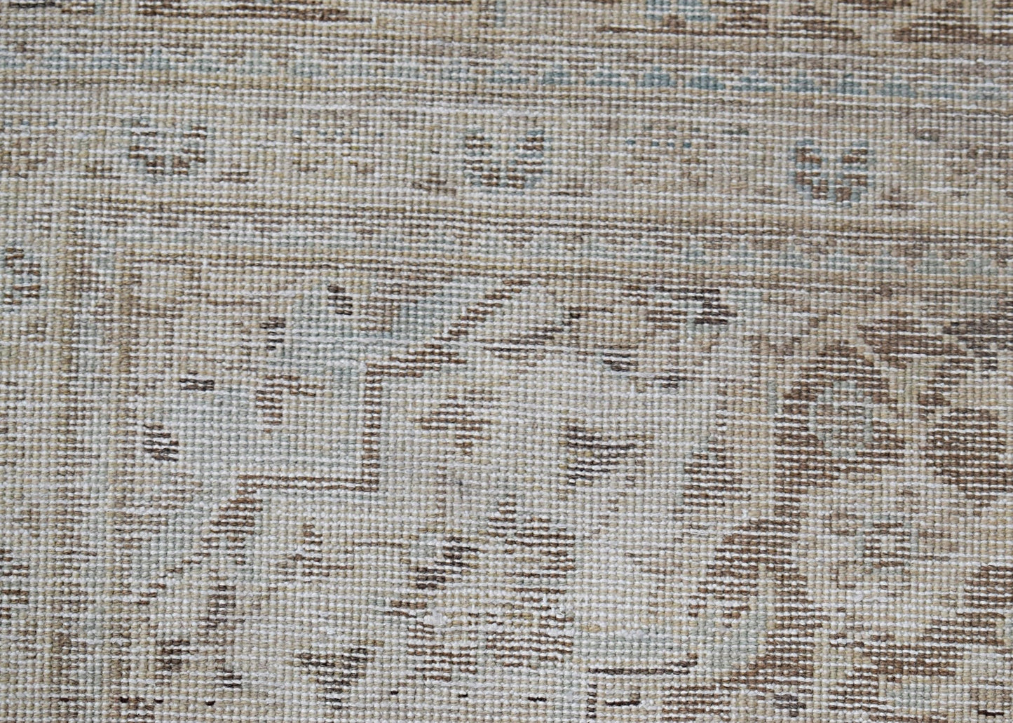 A close-up of a vintage Persian Kerman rug featuring intricate floral patterns in neutral tones.