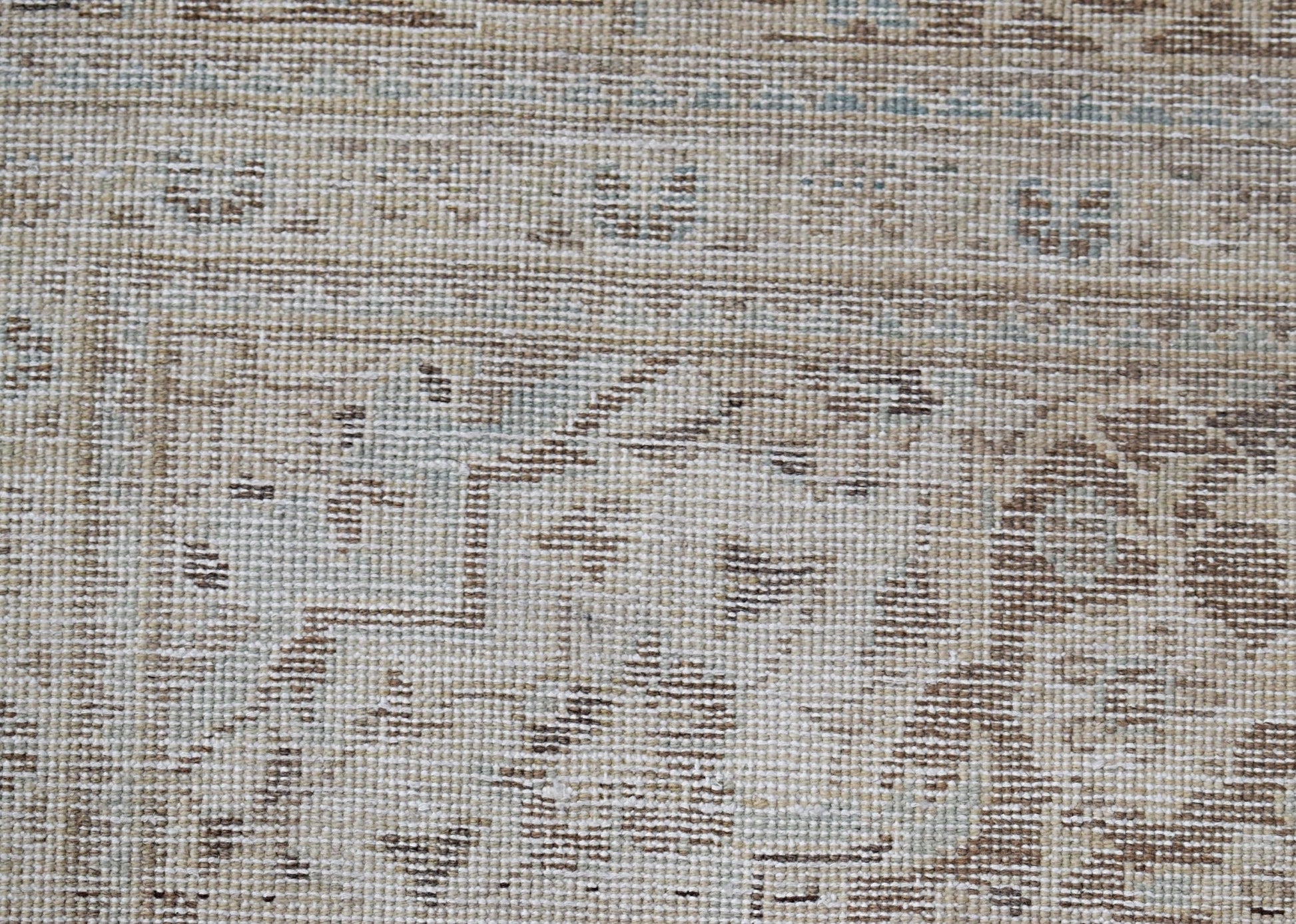 A close-up of a vintage Persian Kerman rug featuring intricate floral patterns in neutral tones.