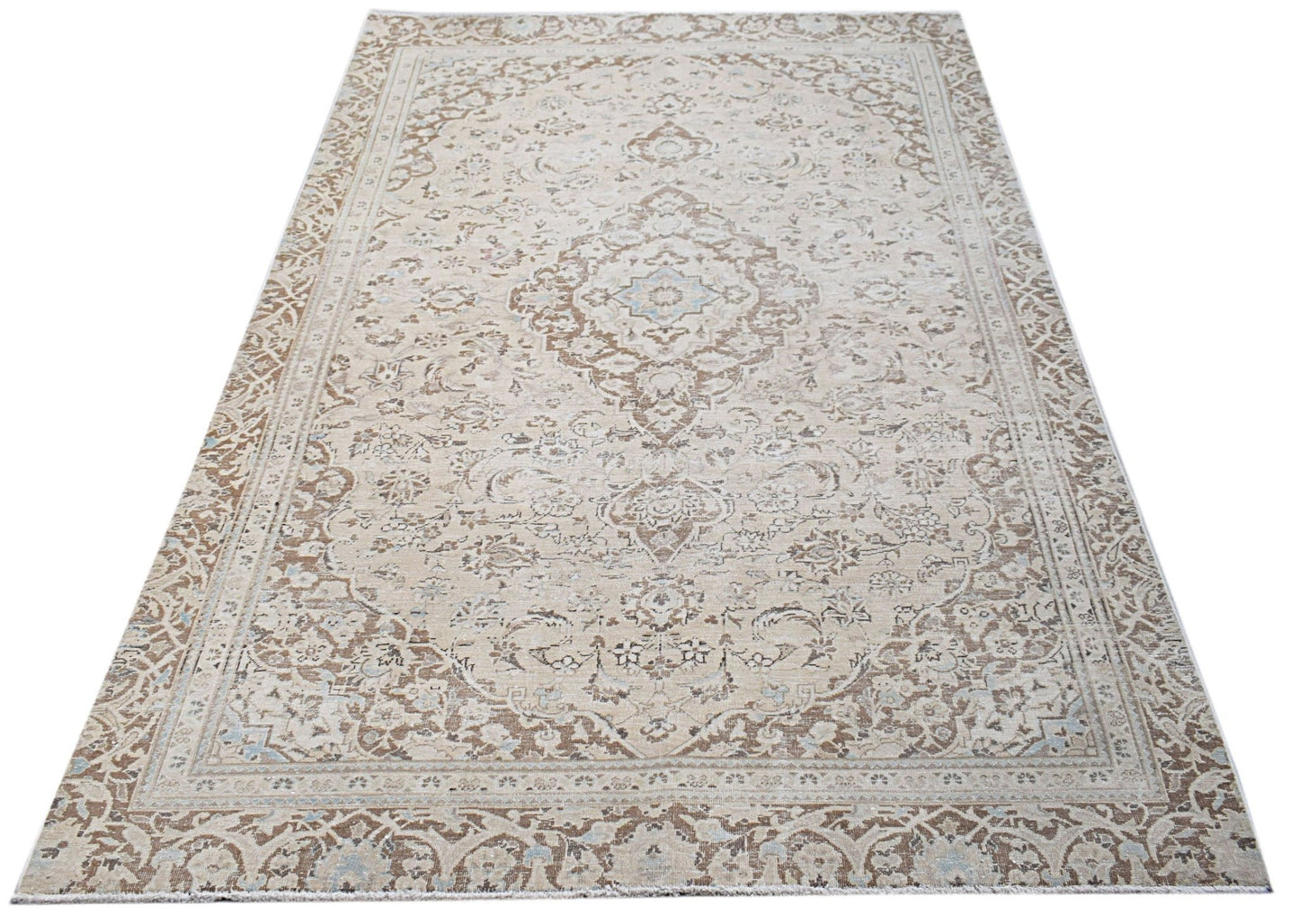 A vintage Persian Kerman rug featuring a central medallion and intricate floral patterns in beige.