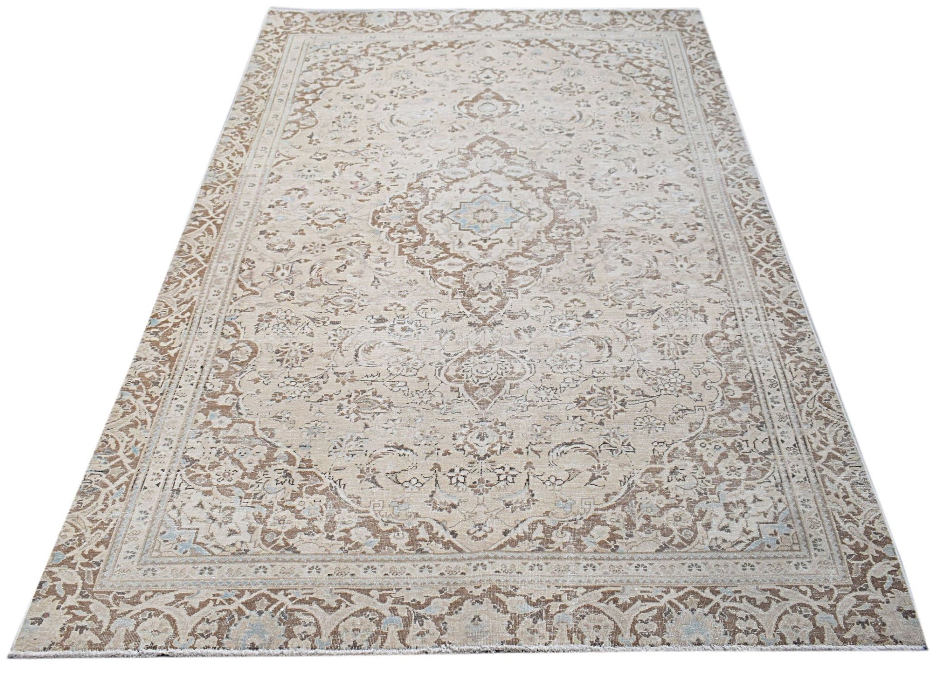 A vintage Persian Kerman rug featuring a central medallion and intricate floral patterns in beige.