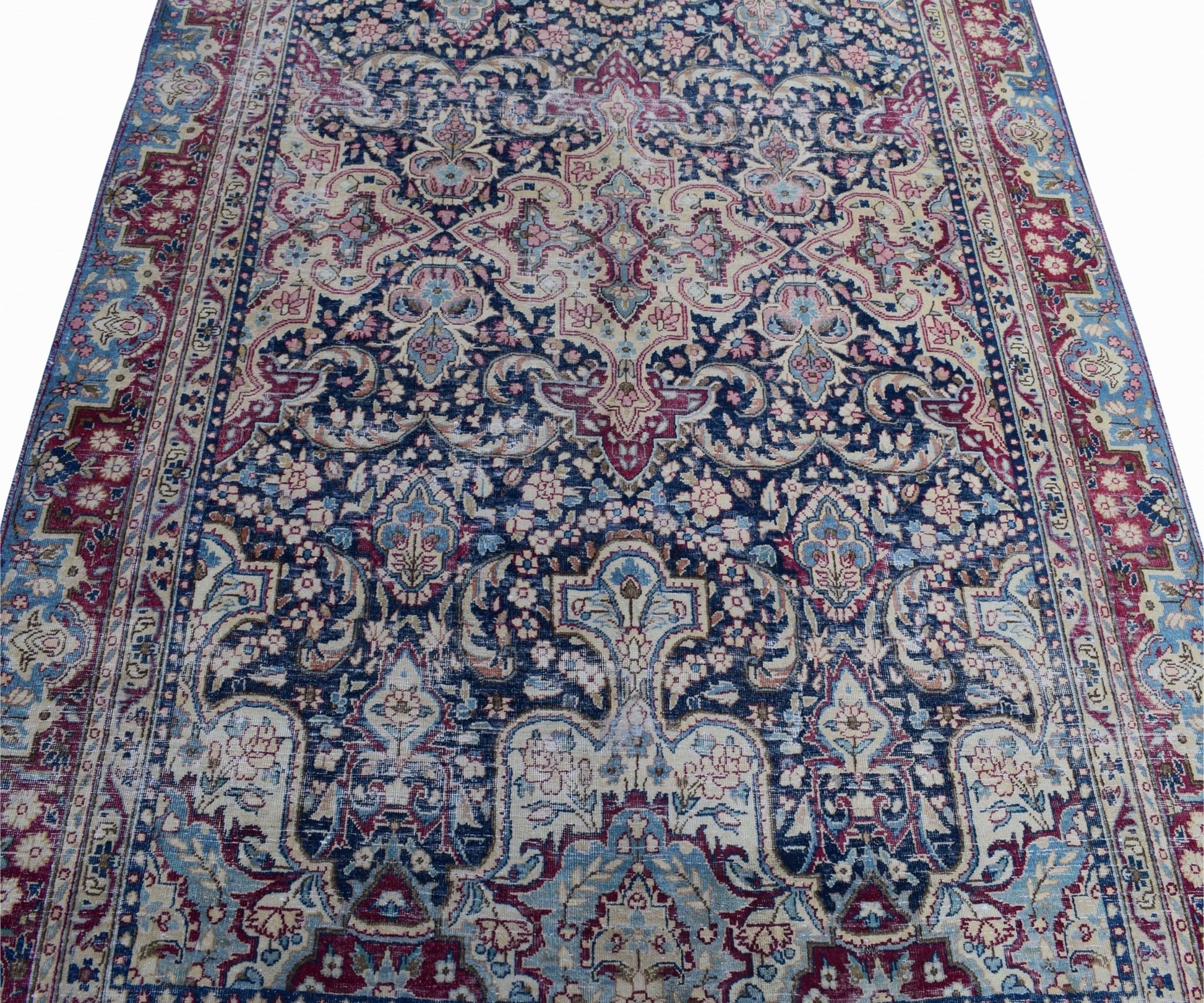 A vintage Persian Kerman rug featuring an intricate floral medallion design in blue and red tones.