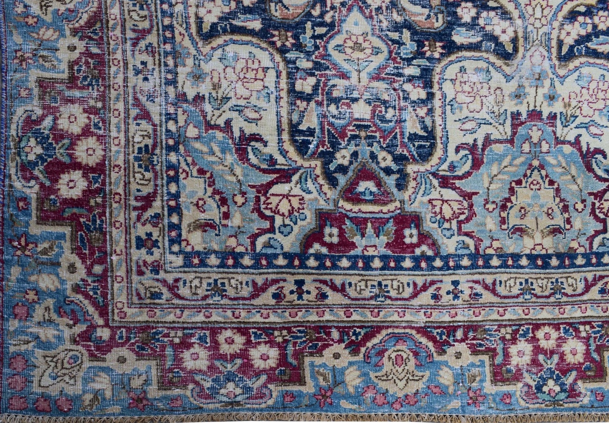 A vintage Persian Kerman rug featuring an intricate floral medallion design in blue and red tones.