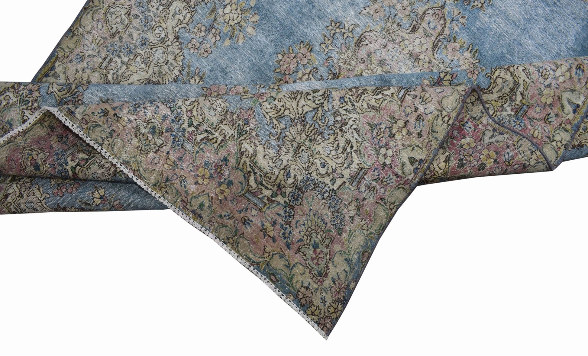 A vintage Persian Kerman rug featuring an intricate floral pattern in blue, pink, and beige tones.