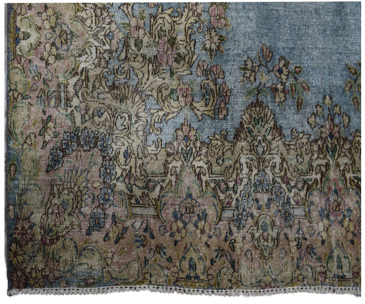 A vintage Persian Kerman rug featuring intricate floral patterns in soft blue and muted tones.