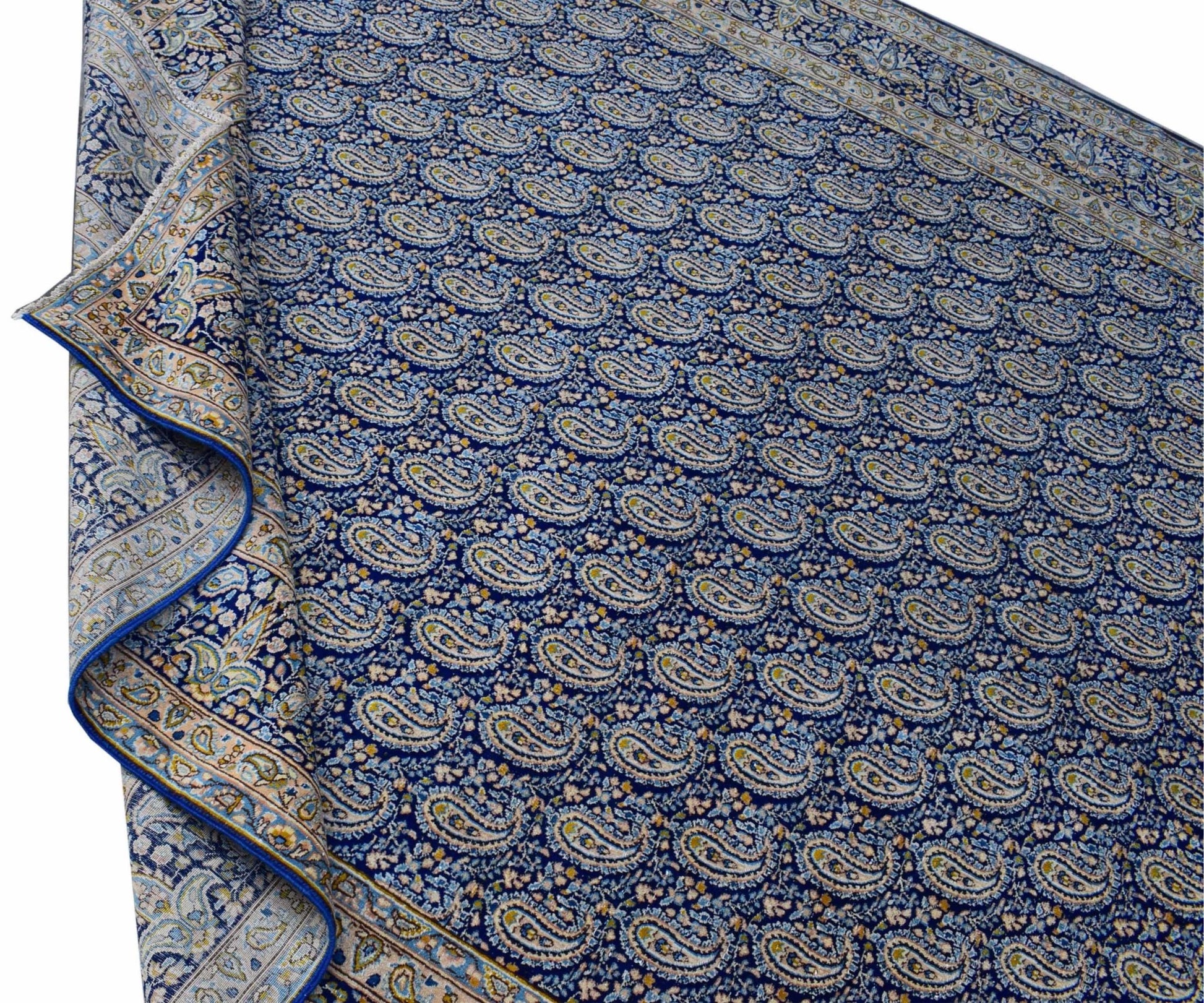 A vintage Persian Kerman rug featuring a dense blue field with an intricate repeating paisley motif.