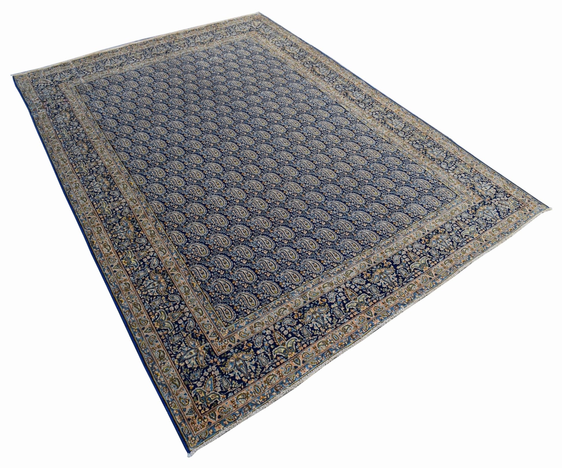 A vintage Persian Kerman rug featuring an all-over blue paisley pattern and a detailed floral border.