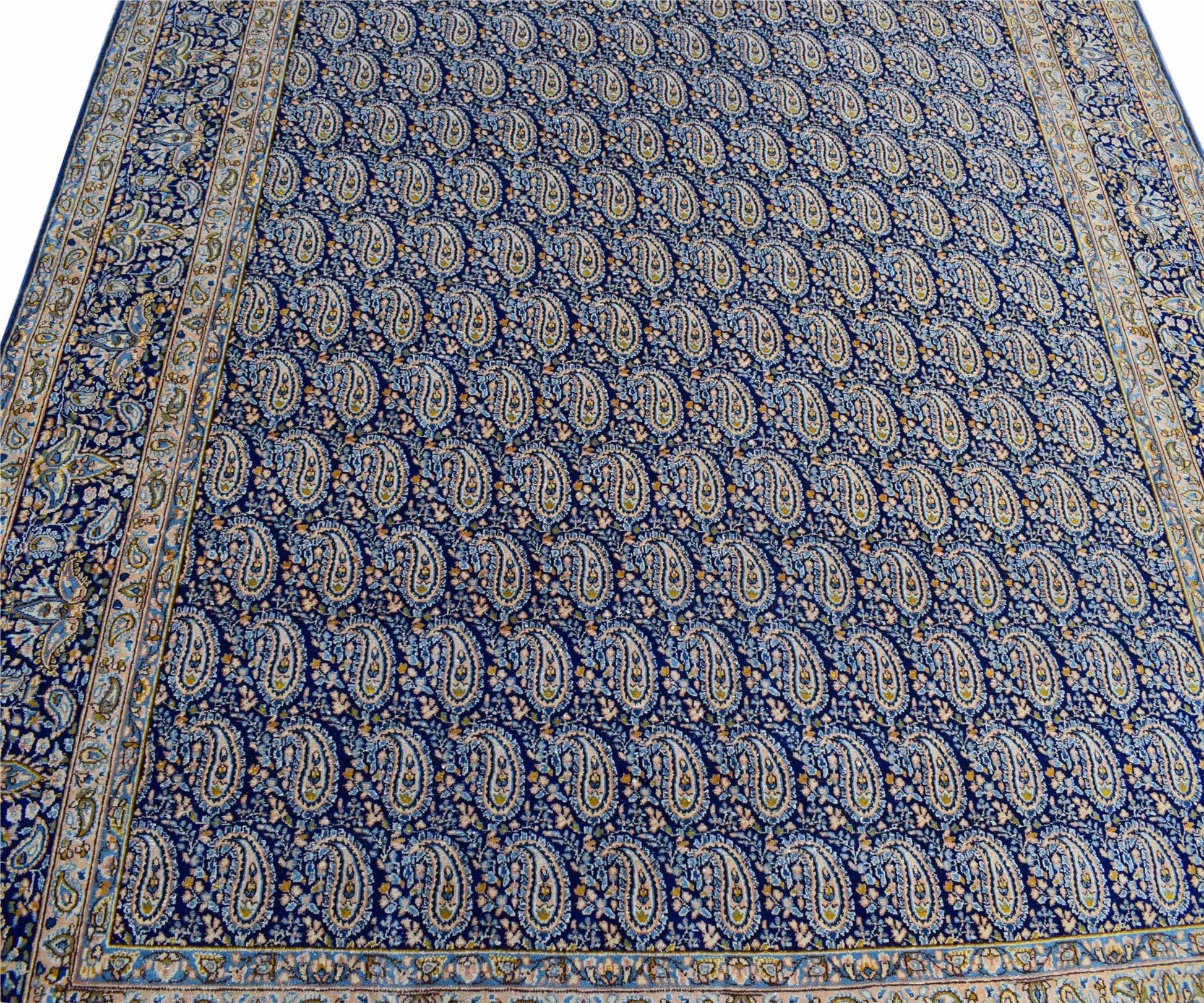 A vintage Persian Kerman rug featuring a dense, repeating paisley pattern in blue and cream tones.