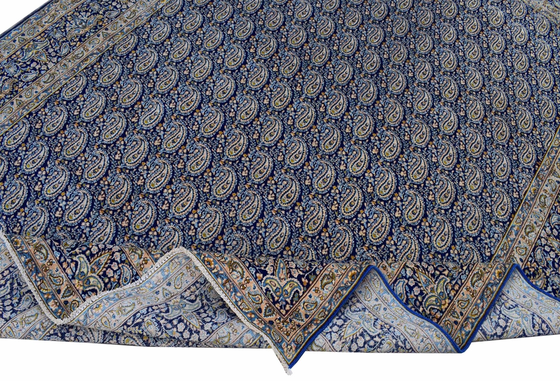 A vintage Persian Kerman rug featuring a dense blue field with an all-over paisley pattern.