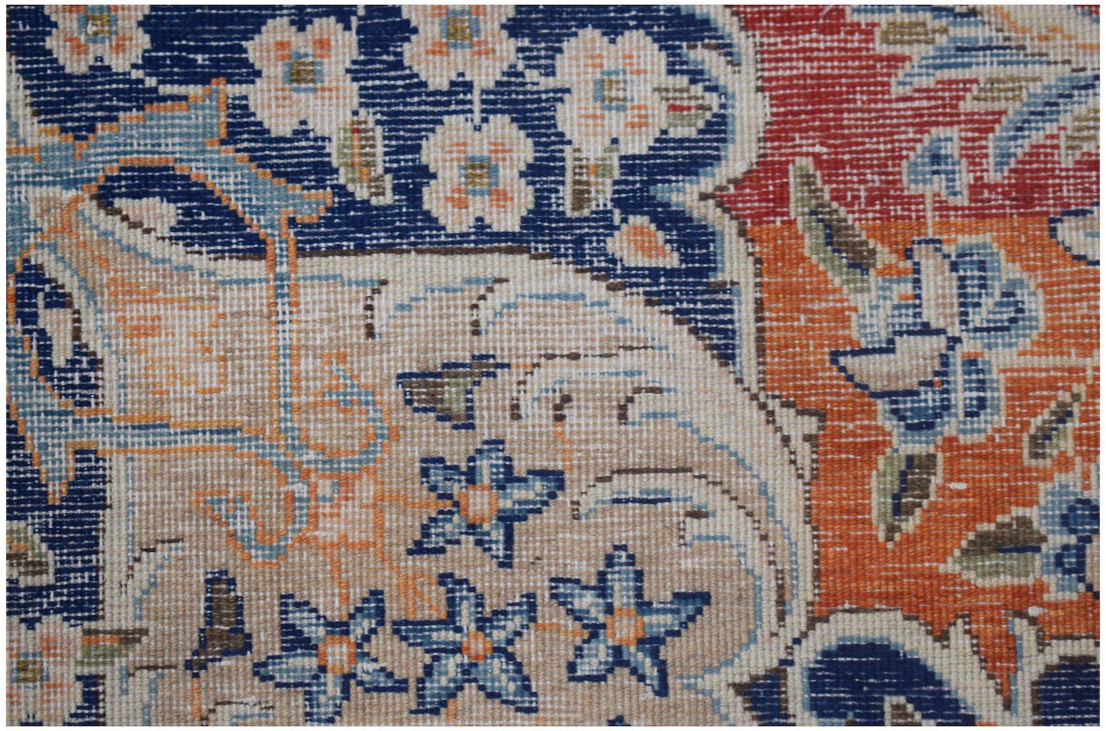Close-up of a vintage Persian Kerman rug featuring intricate floral patterns in blue and orange.