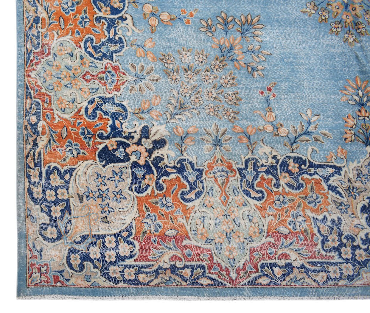 A vintage Persian Kerman rug featuring an intricate floral pattern in blue, orange, and cream.