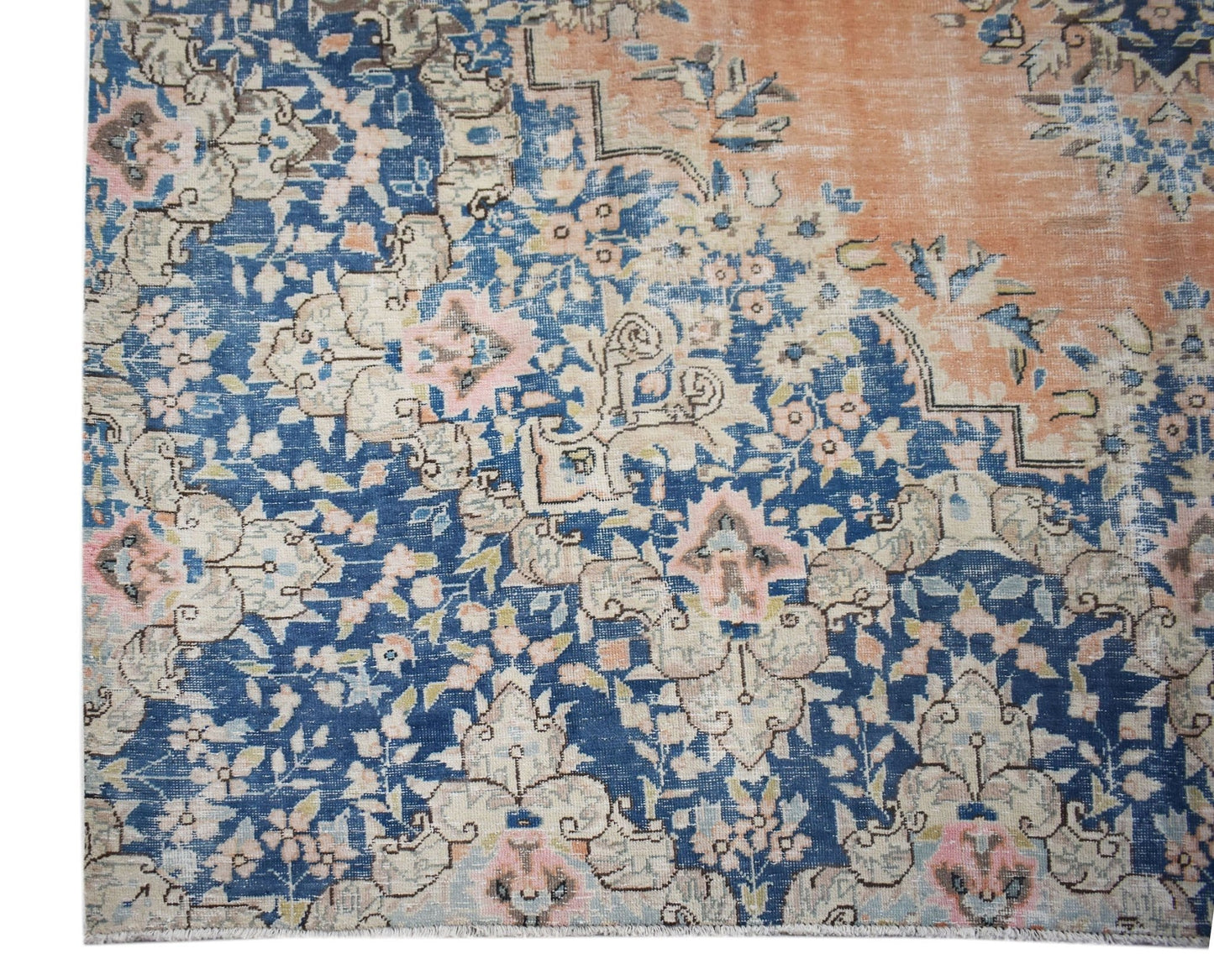 A vintage Persian Kerman rug featuring an intricate floral pattern in blue, peach, and cream tones.