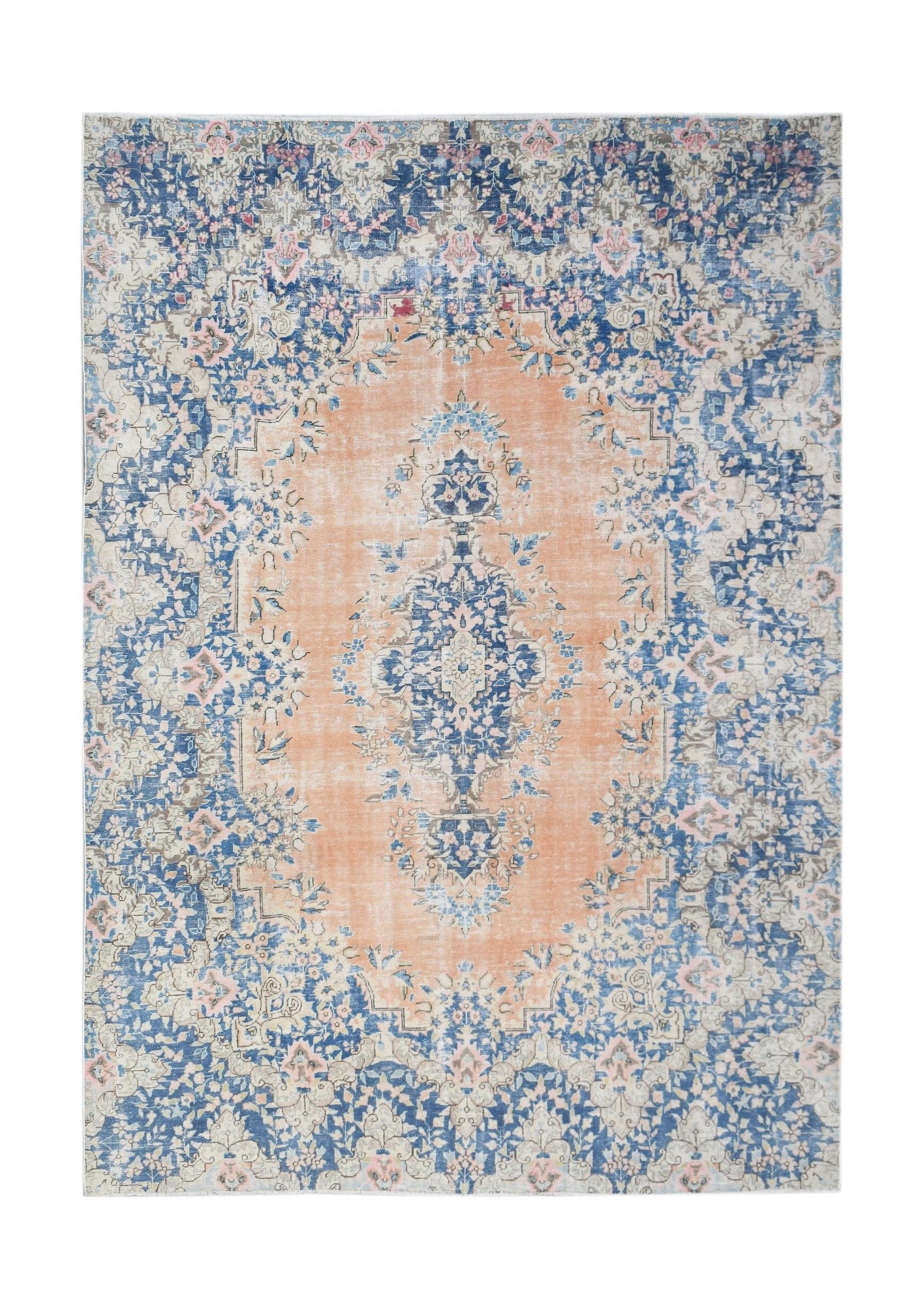 A vintage Persian Kerman rug featuring a central medallion with blue and peach floral patterns.