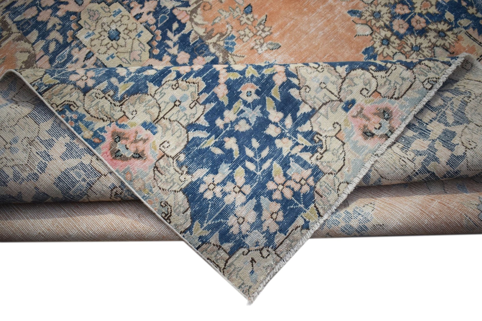A vintage Persian Kerman rug featuring a floral medallion pattern in blue, peach, and cream tones.