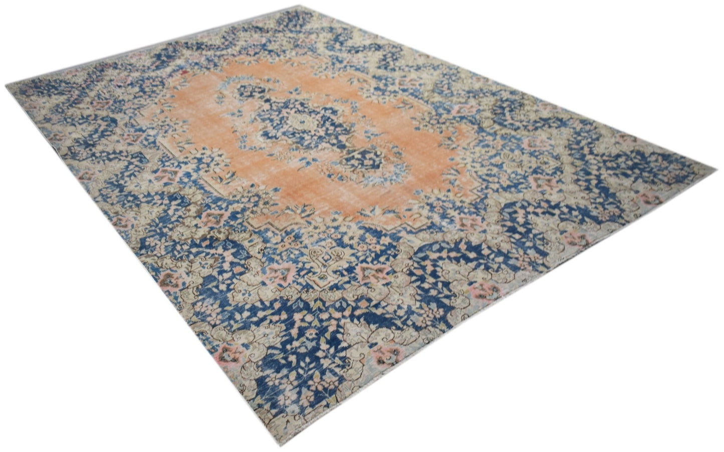 A vintage Persian Kerman rug featuring a central medallion with intricate blue and orange floral patterns.