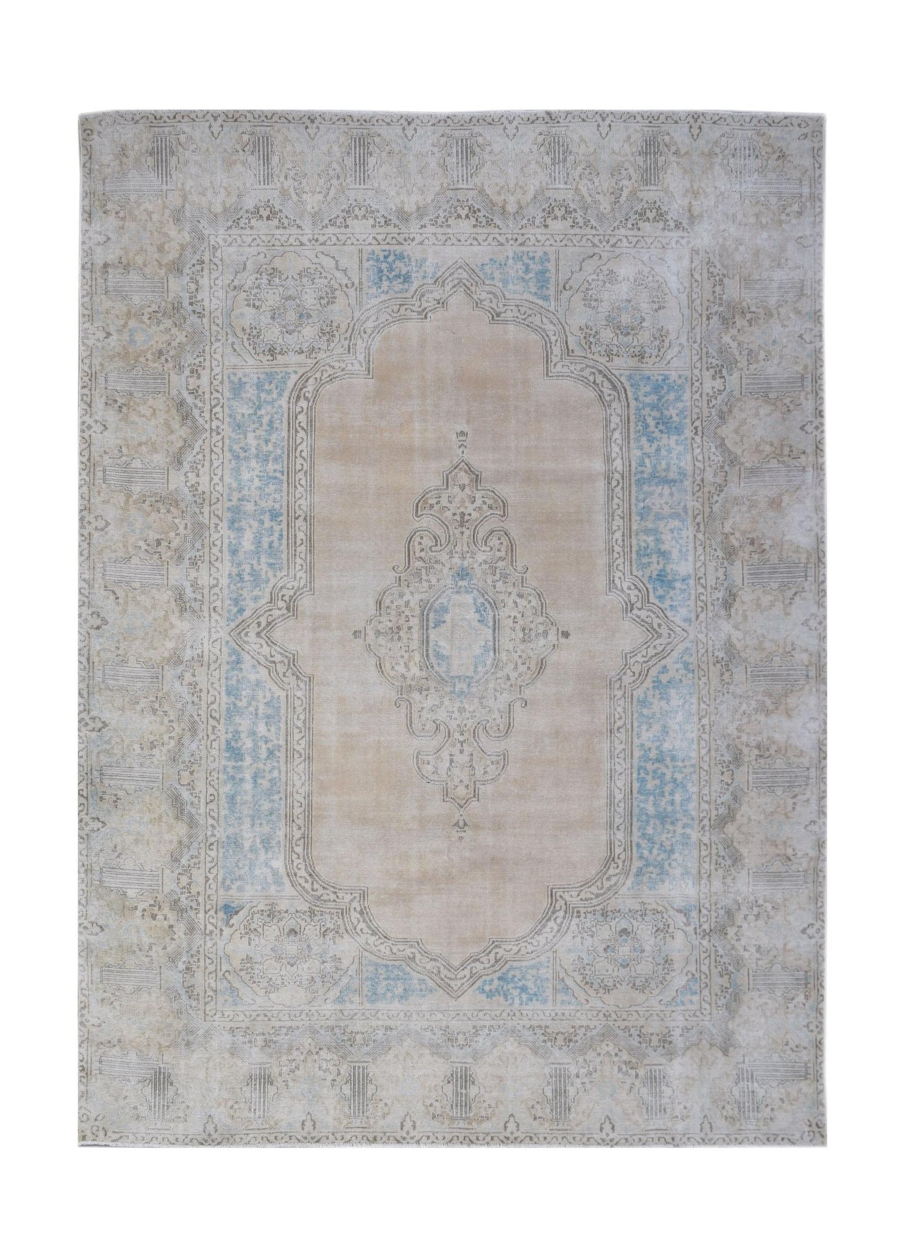 A vintage Persian Kerman rug featuring a central medallion in soft beige and blue tones.