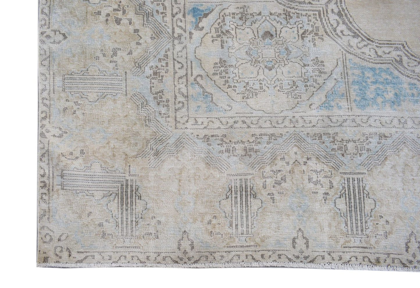 A vintage Persian Kerman rug featuring a faded floral medallion design in beige and soft blue.