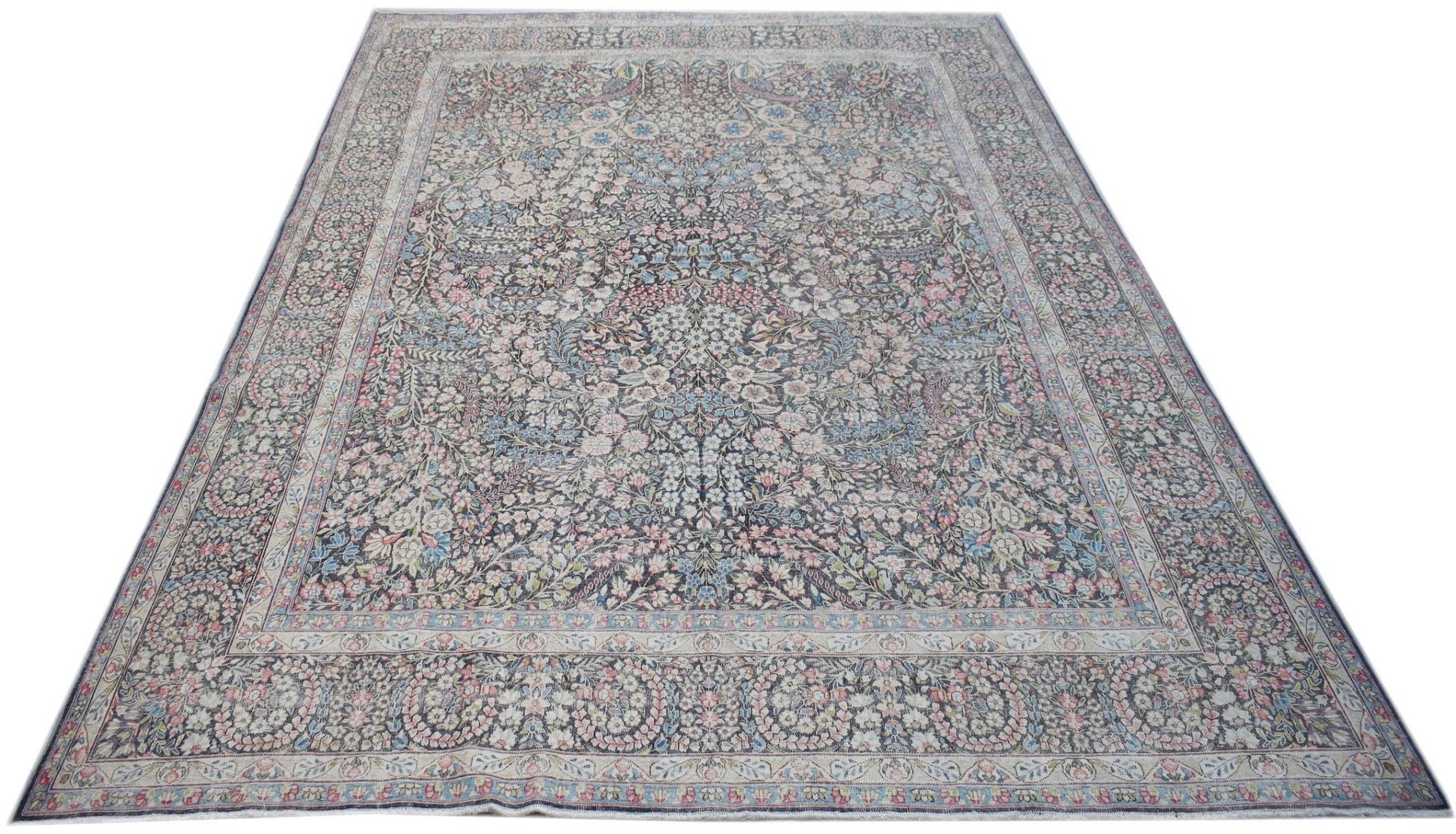 A vintage Persian Kerman rug featuring an intricate floral pattern and a central medallion.