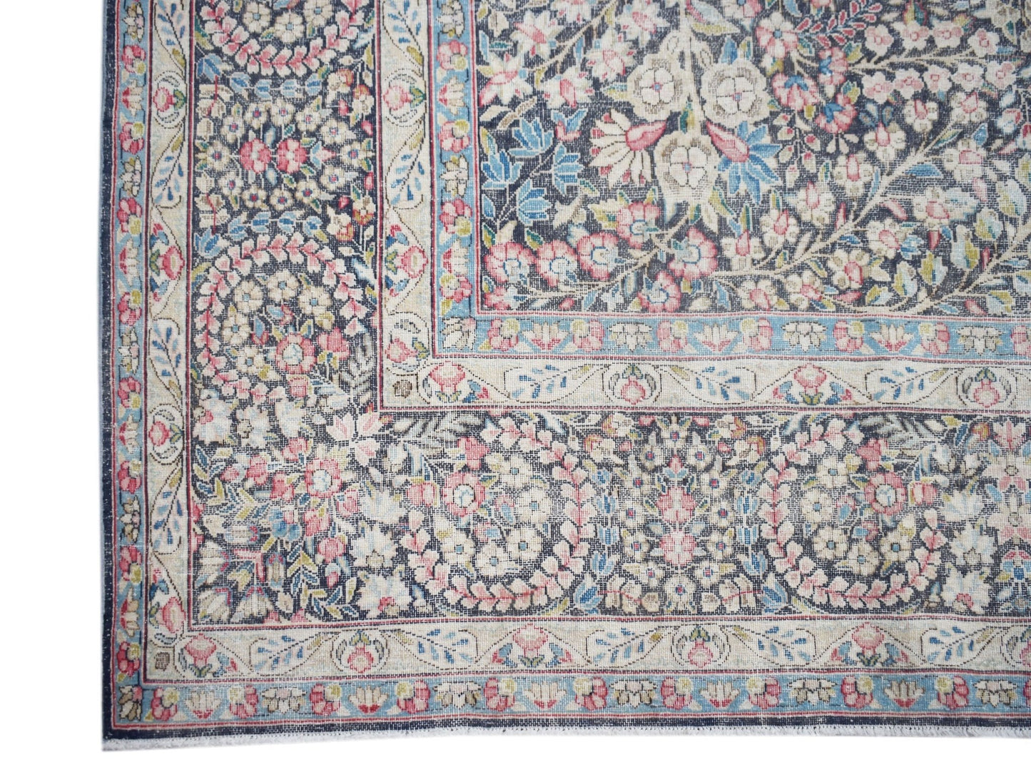 A vintage Persian Kerman rug featuring an intricate floral pattern in soft pink and blue tones.