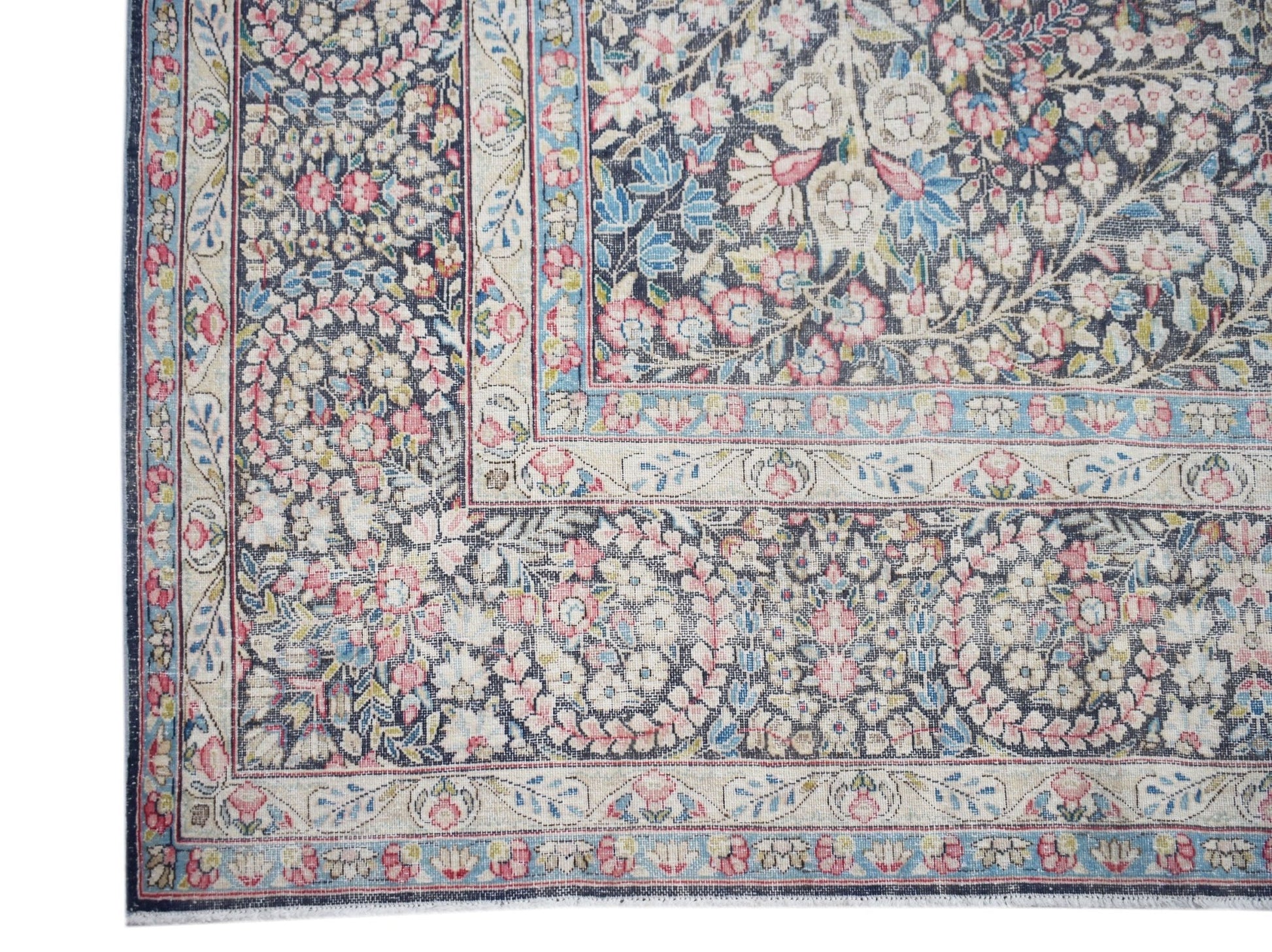 A vintage Persian Kerman rug featuring an intricate floral pattern in soft pink and blue tones.