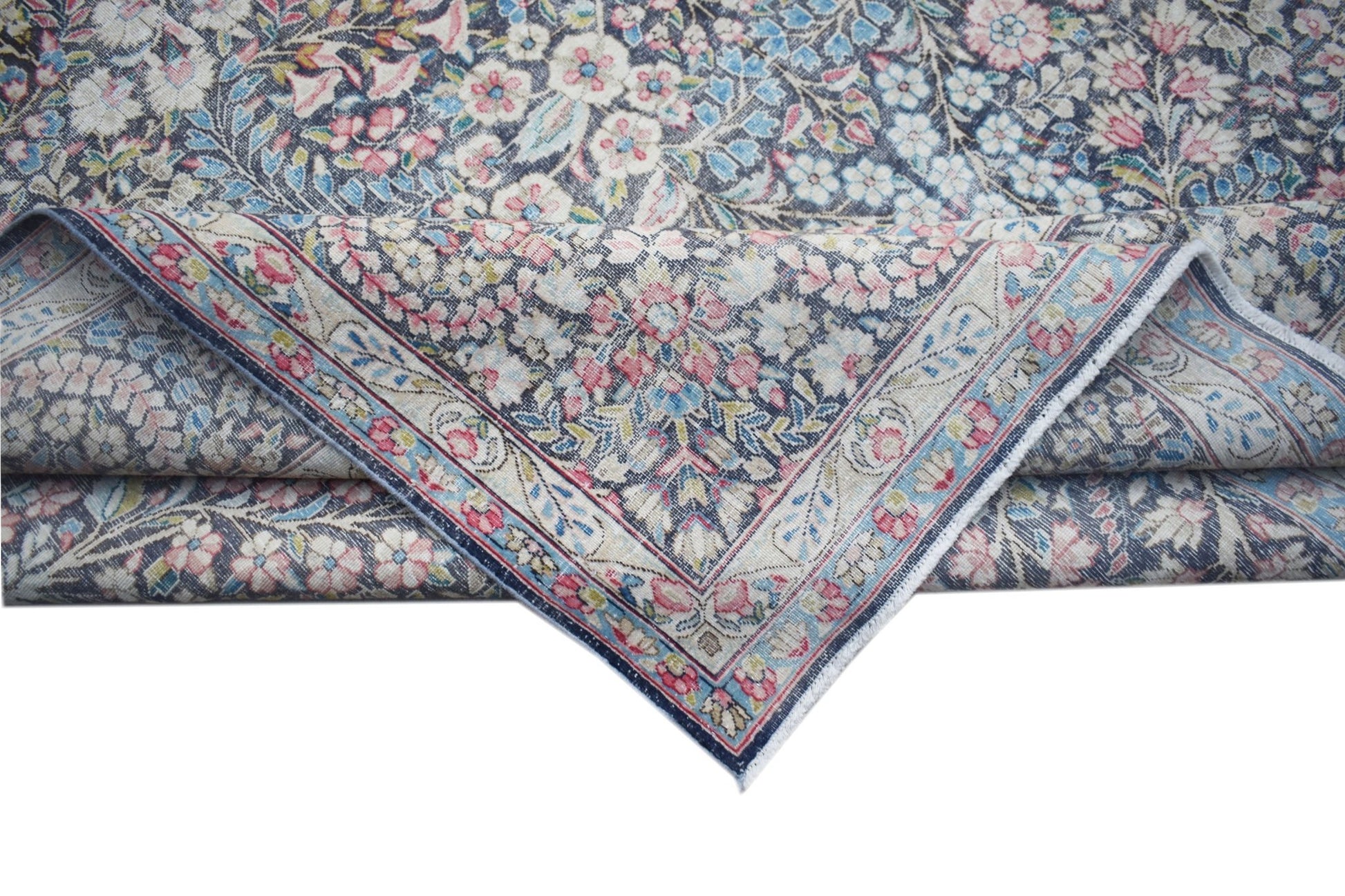 A vintage Persian Kerman rug featuring an intricate floral pattern in soft pink and blue tones.