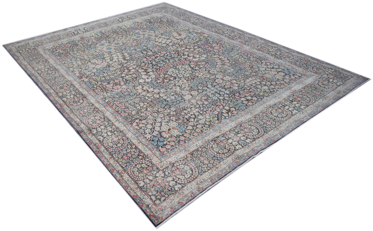 A vintage Persian Kerman rug featuring an intricate floral pattern in soft, muted tones.