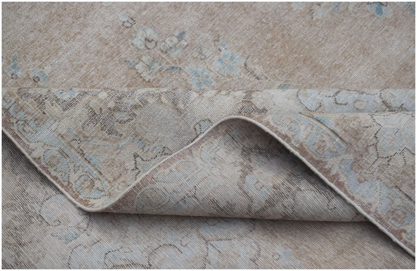 A vintage Persian Kerman rug featuring a faded floral pattern in soft beige and blue tones.