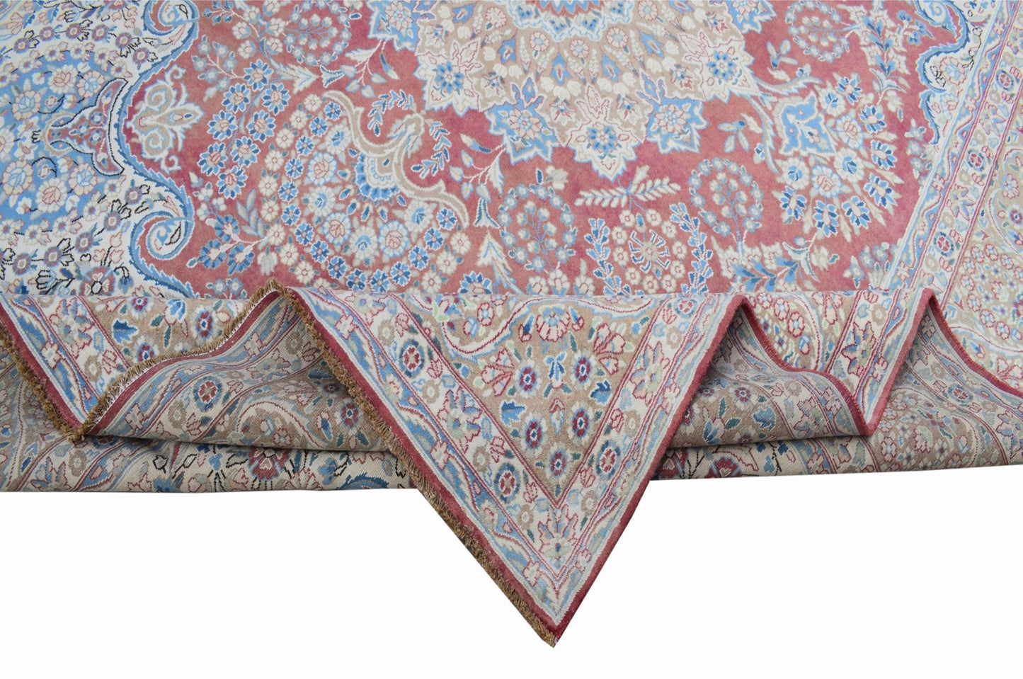 A vintage Persian Kerman rug featuring a floral medallion design in shades of pink and blue.