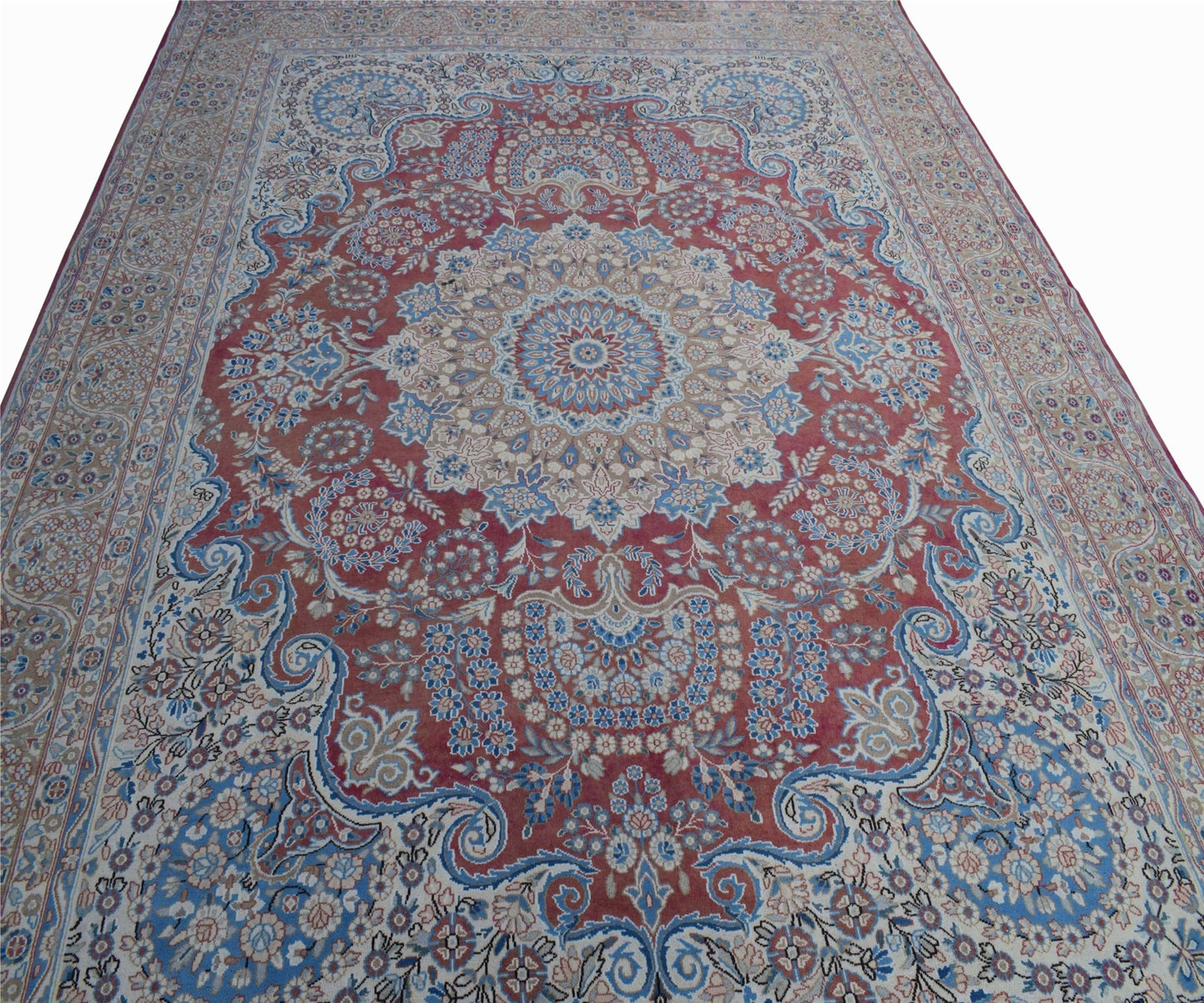 A vintage Persian Kerman rug featuring a central medallion and intricate floral patterns in red and blue.