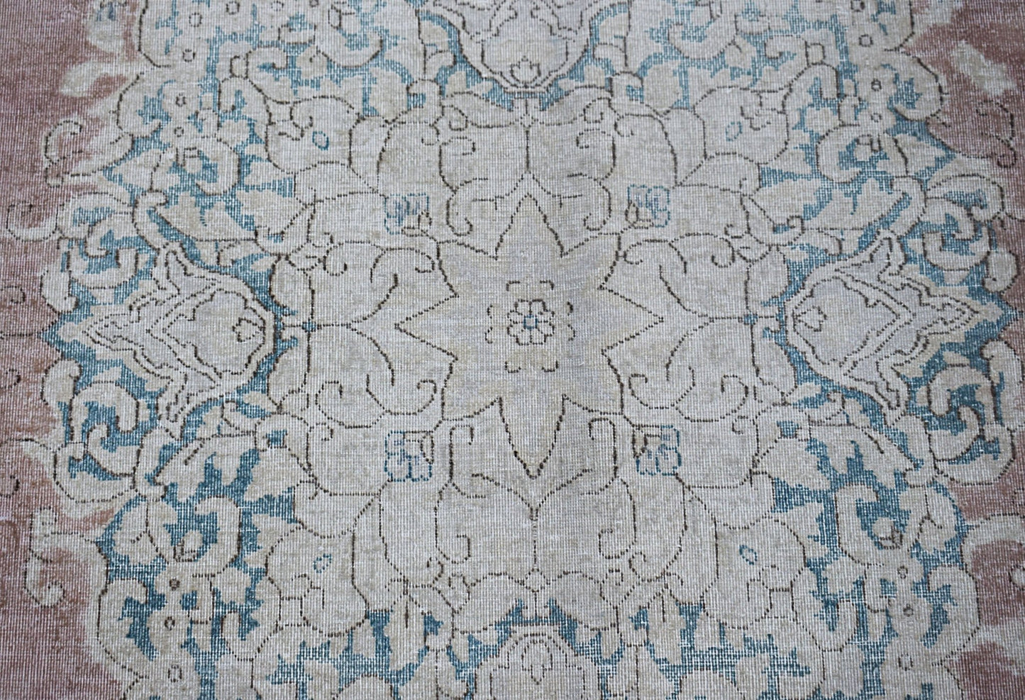 A vintage Persian Kerman rug featuring a central floral medallion in soft blue and beige tones.