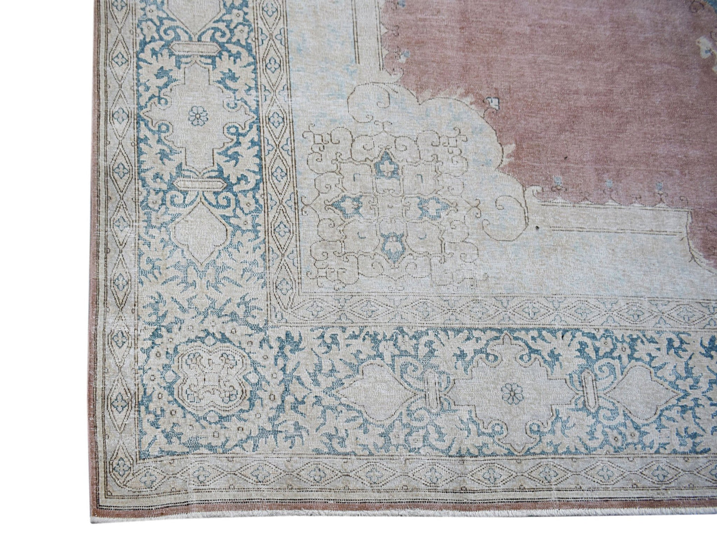 A vintage Persian Kerman rug featuring a dusty pink field with intricate blue floral borders.