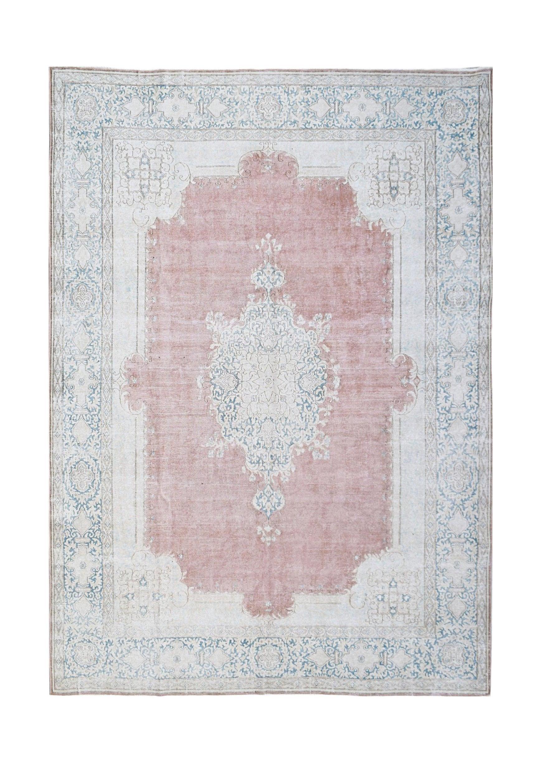 A vintage Persian Kerman rug featuring a central medallion in soft pink and blue floral patterns.