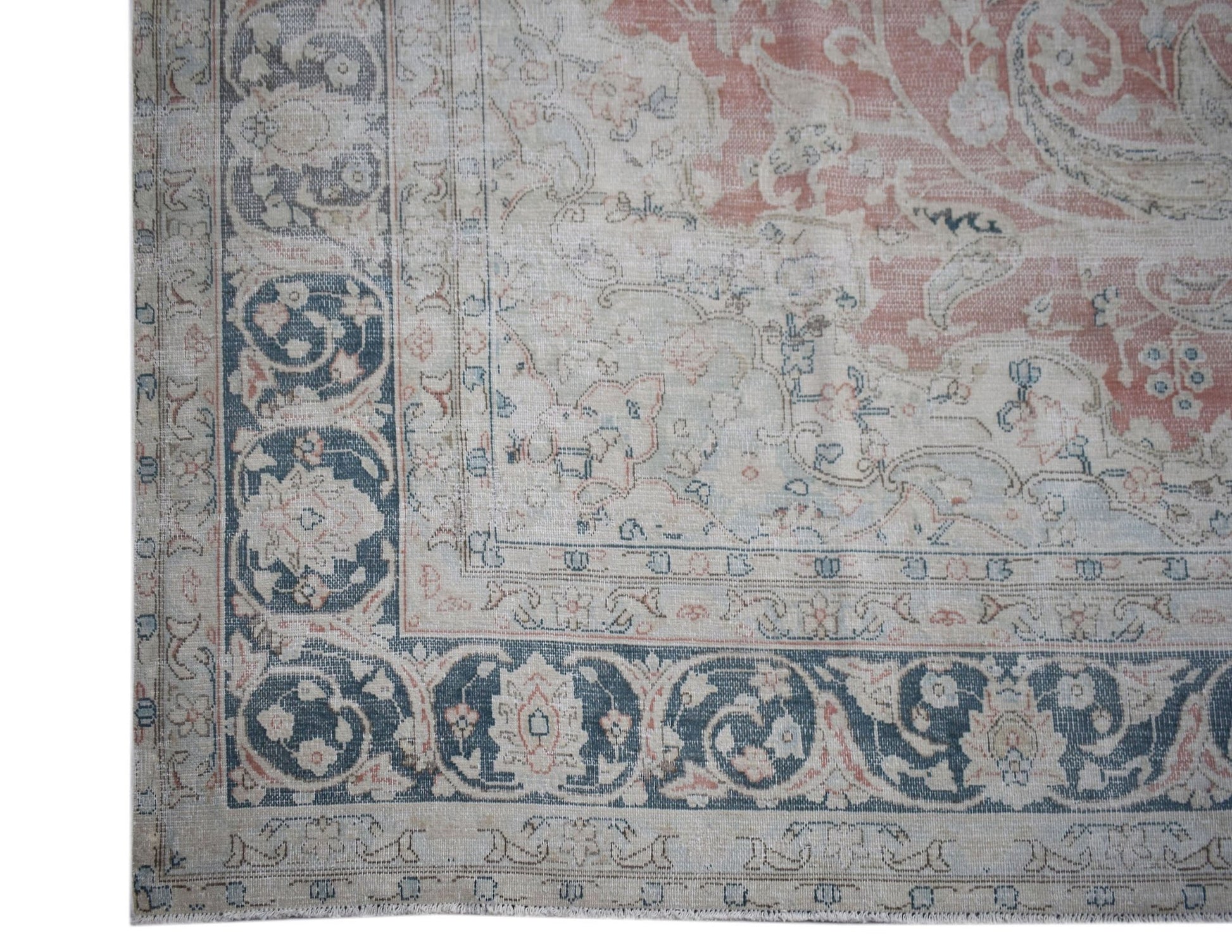 A vintage Persian Kerman rug featuring a faded floral medallion design in soft pink and blue tones.