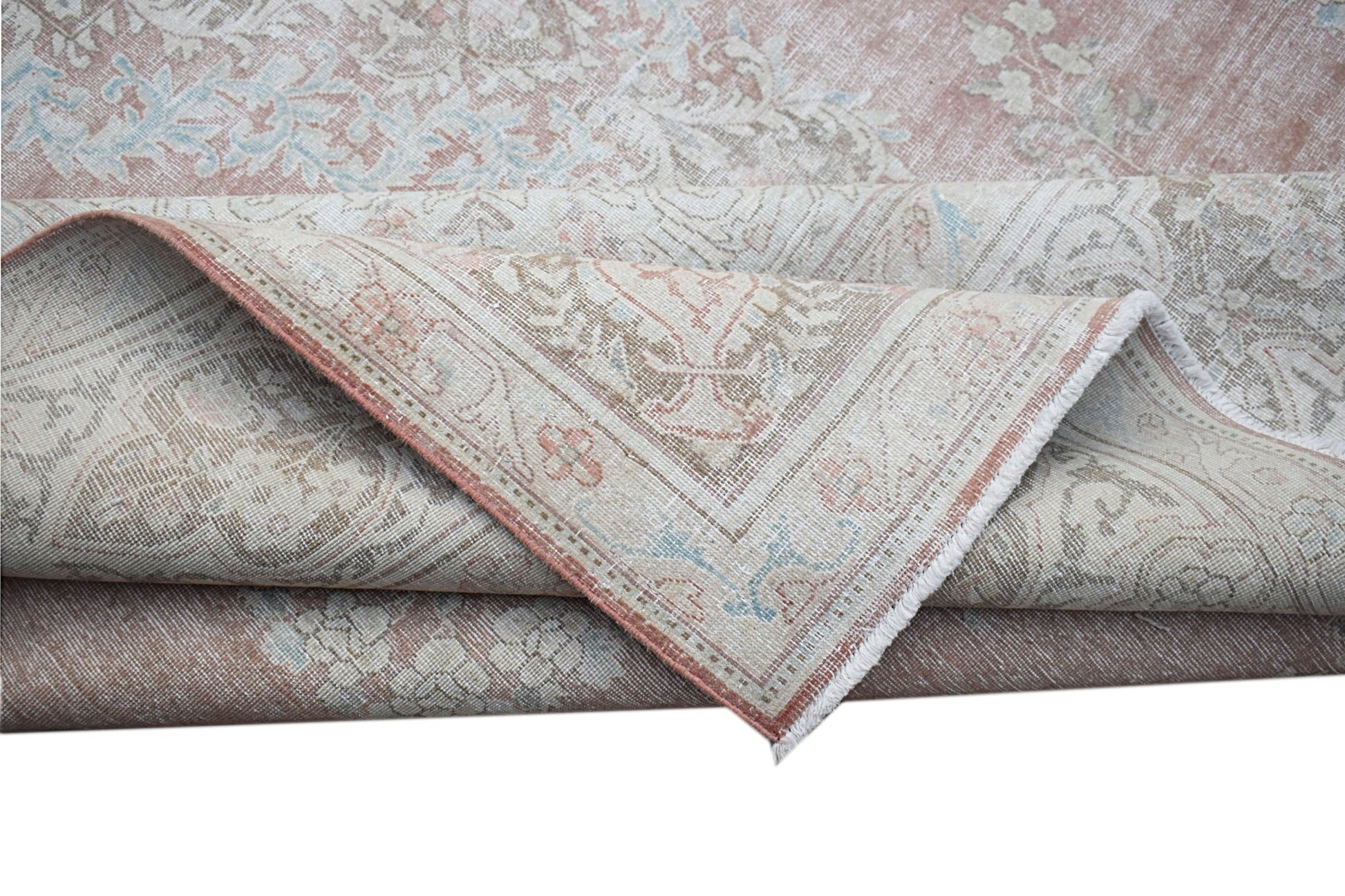 A vintage Persian Kerman rug featuring a soft pink palette with intricate floral patterns.