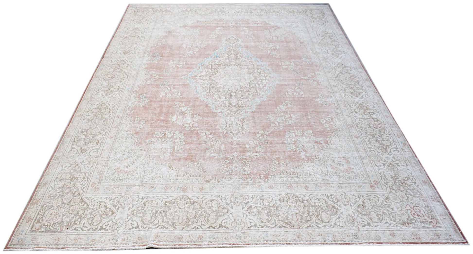 A vintage Persian Kerman rug featuring a central medallion and intricate floral patterns in soft pink.