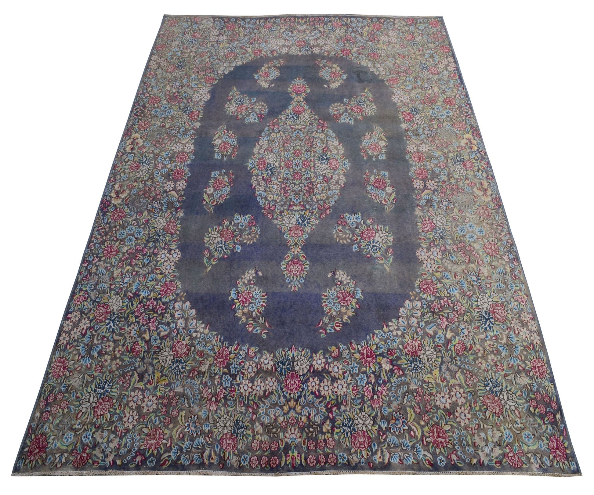 A vintage Persian Kerman rug featuring a central floral medallion on a blue field.