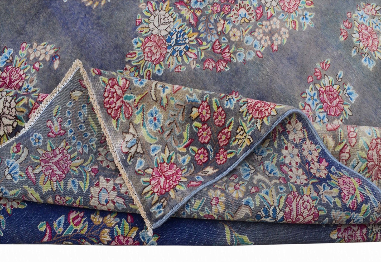 A vintage Persian Kerman rug featuring an intricate floral pattern on a blue background.