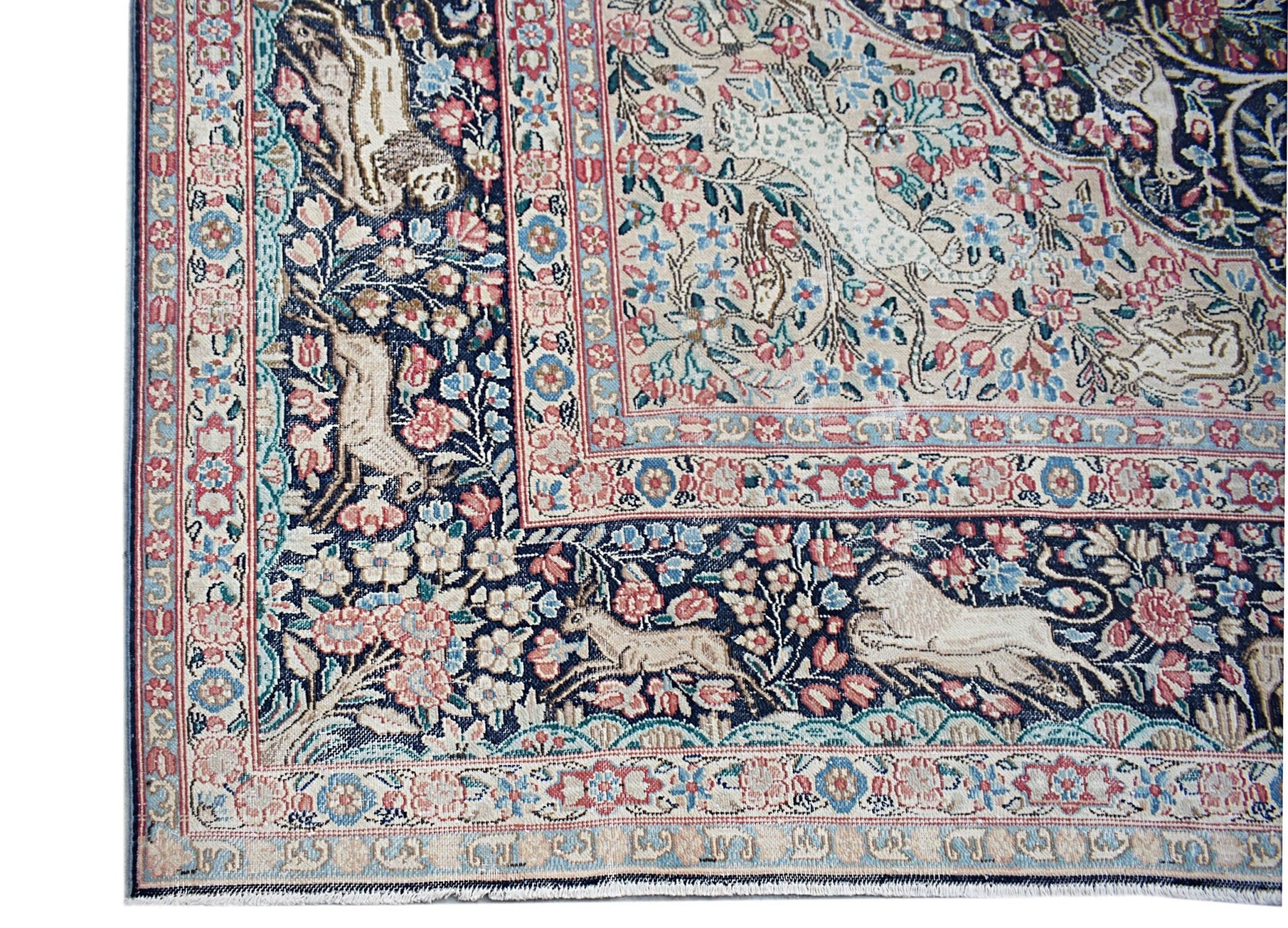 A vintage Persian Kerman rug featuring intricate floral patterns and animal motifs.