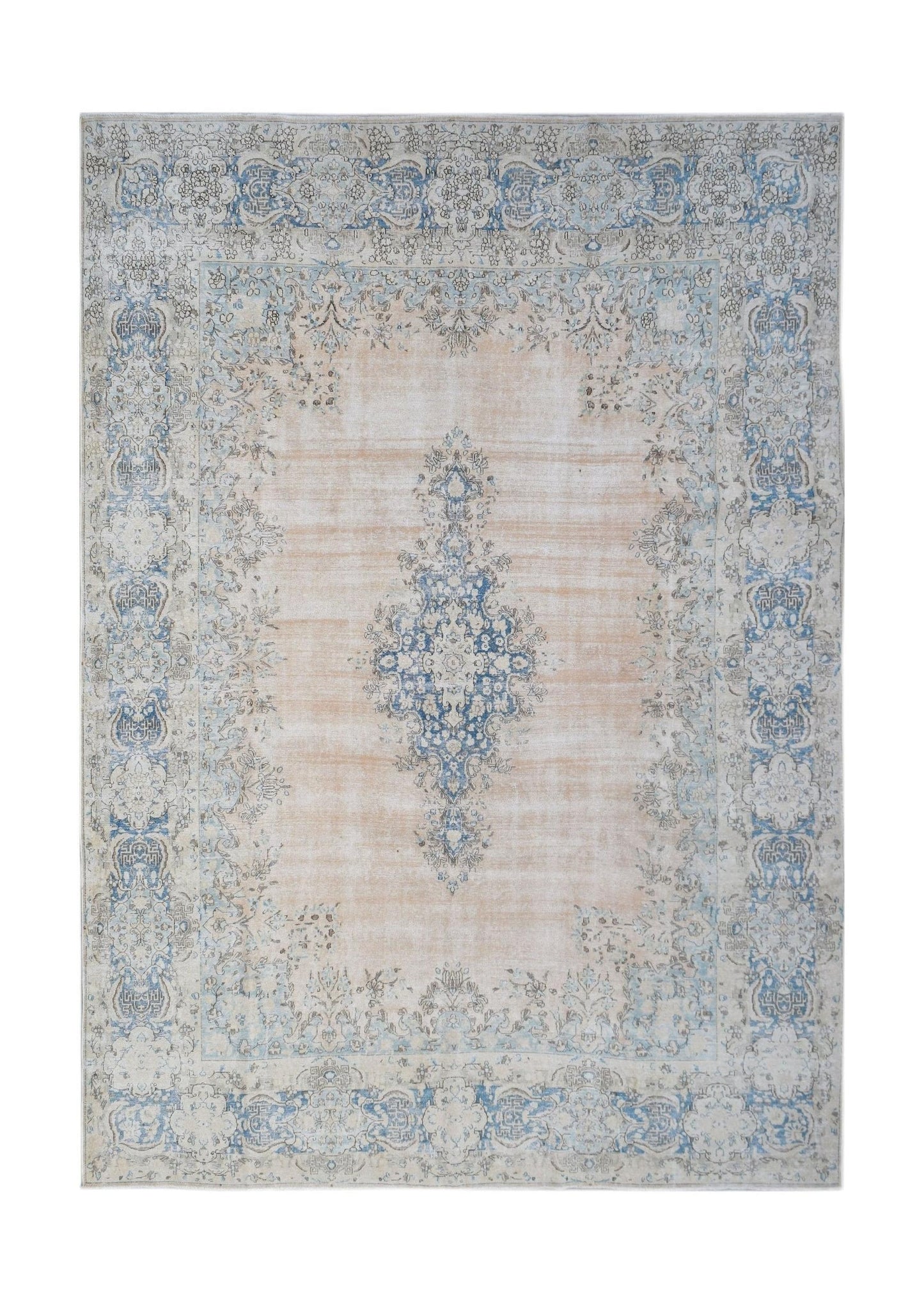 A vintage Persian Kerman rug featuring a central blue medallion on a soft peach field.