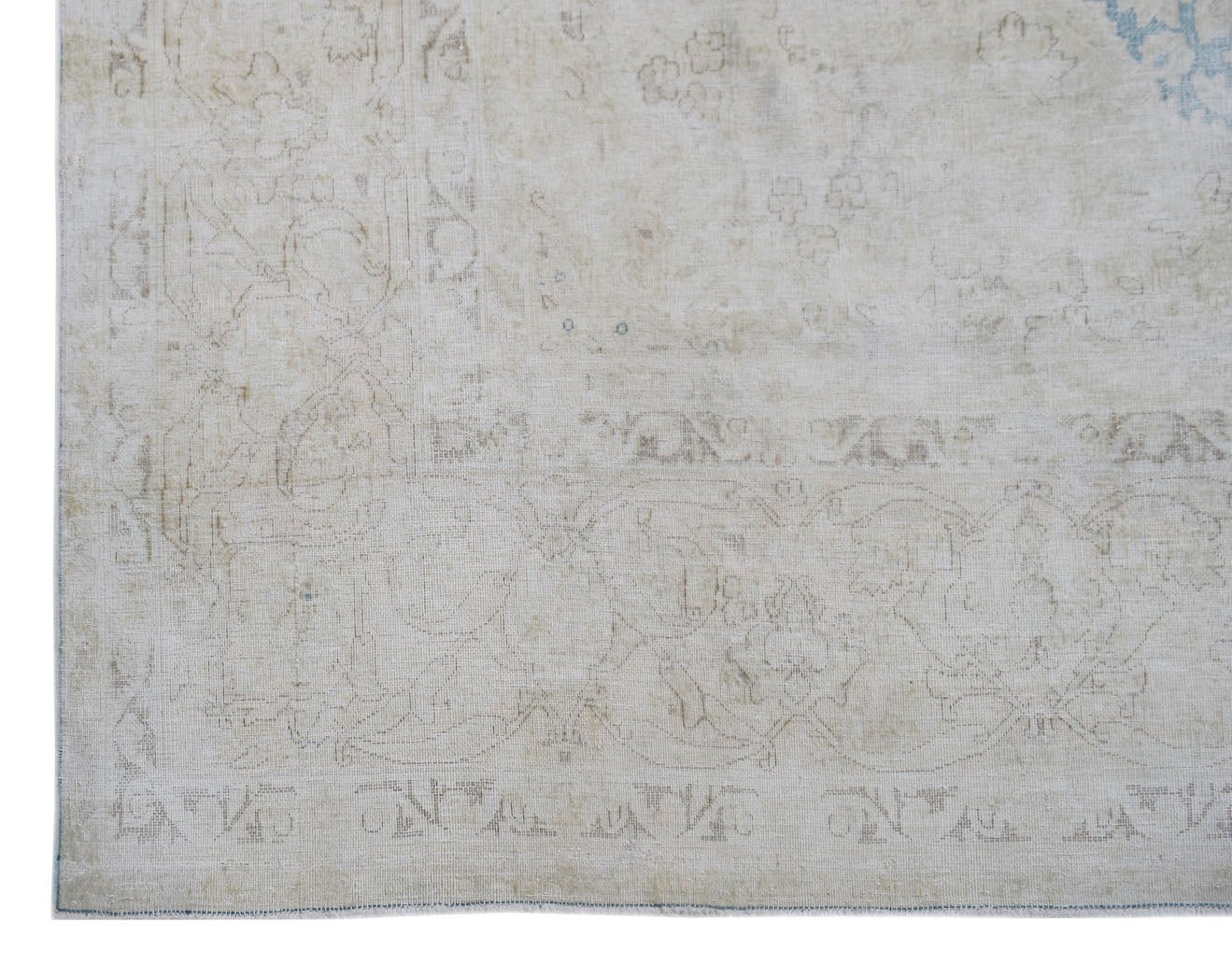 A vintage Persian Kerman rug featuring a faded, intricate floral pattern in neutral tones.