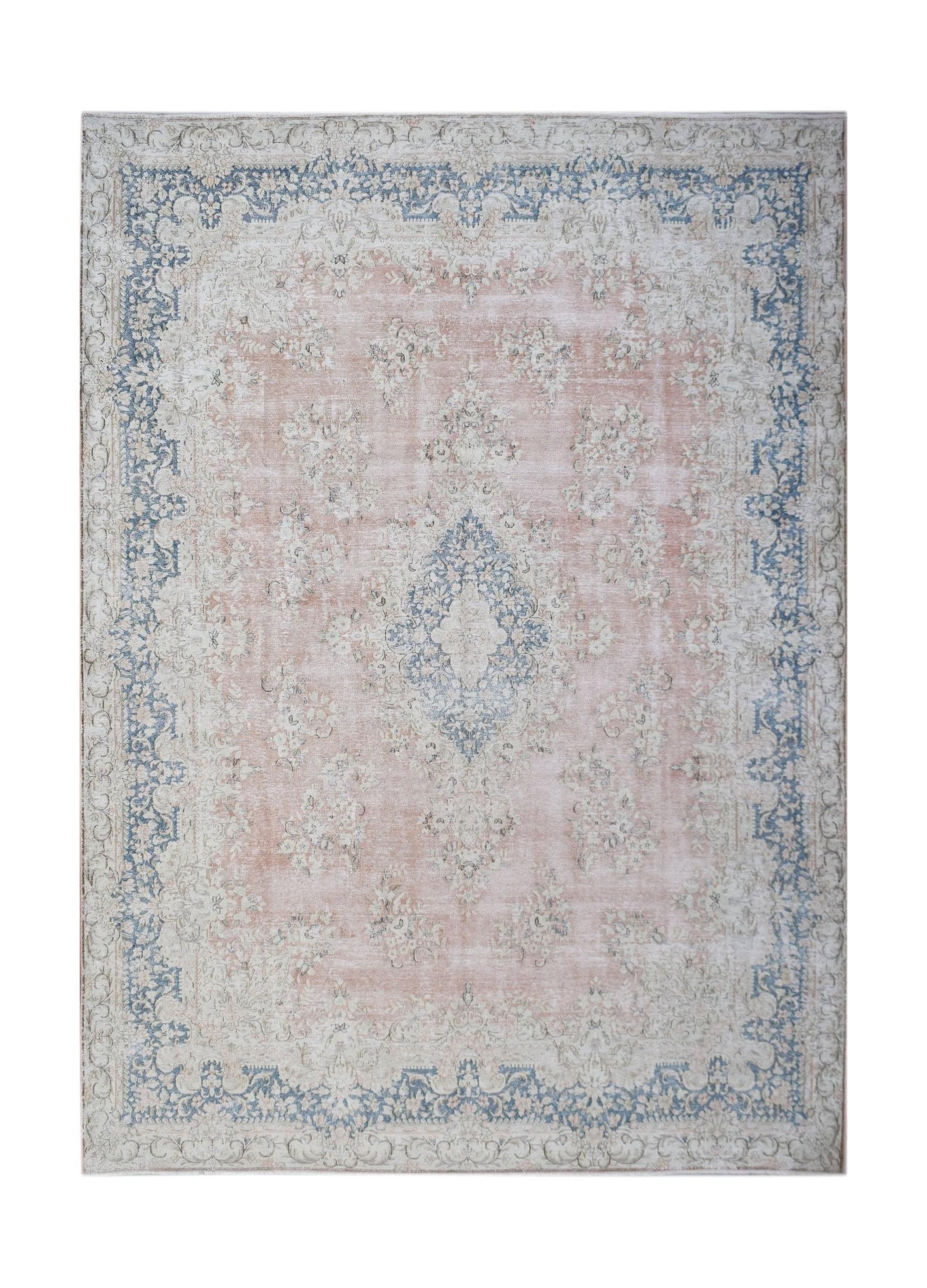 A vintage Persian Kerman rug featuring a central medallion and floral motifs in soft pink and blue.