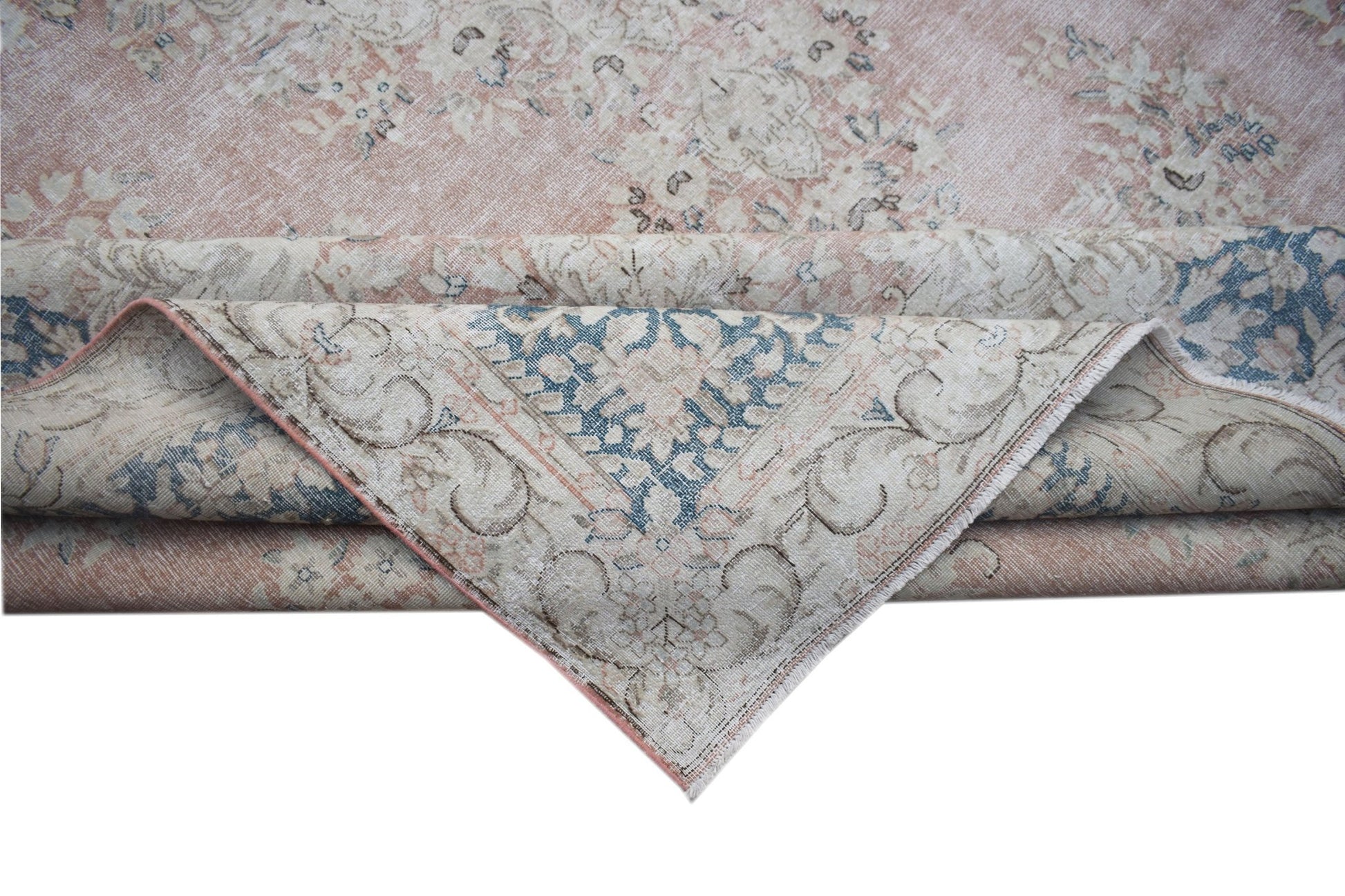 A vintage Persian Kerman rug featuring a soft pink and blue floral medallion design.