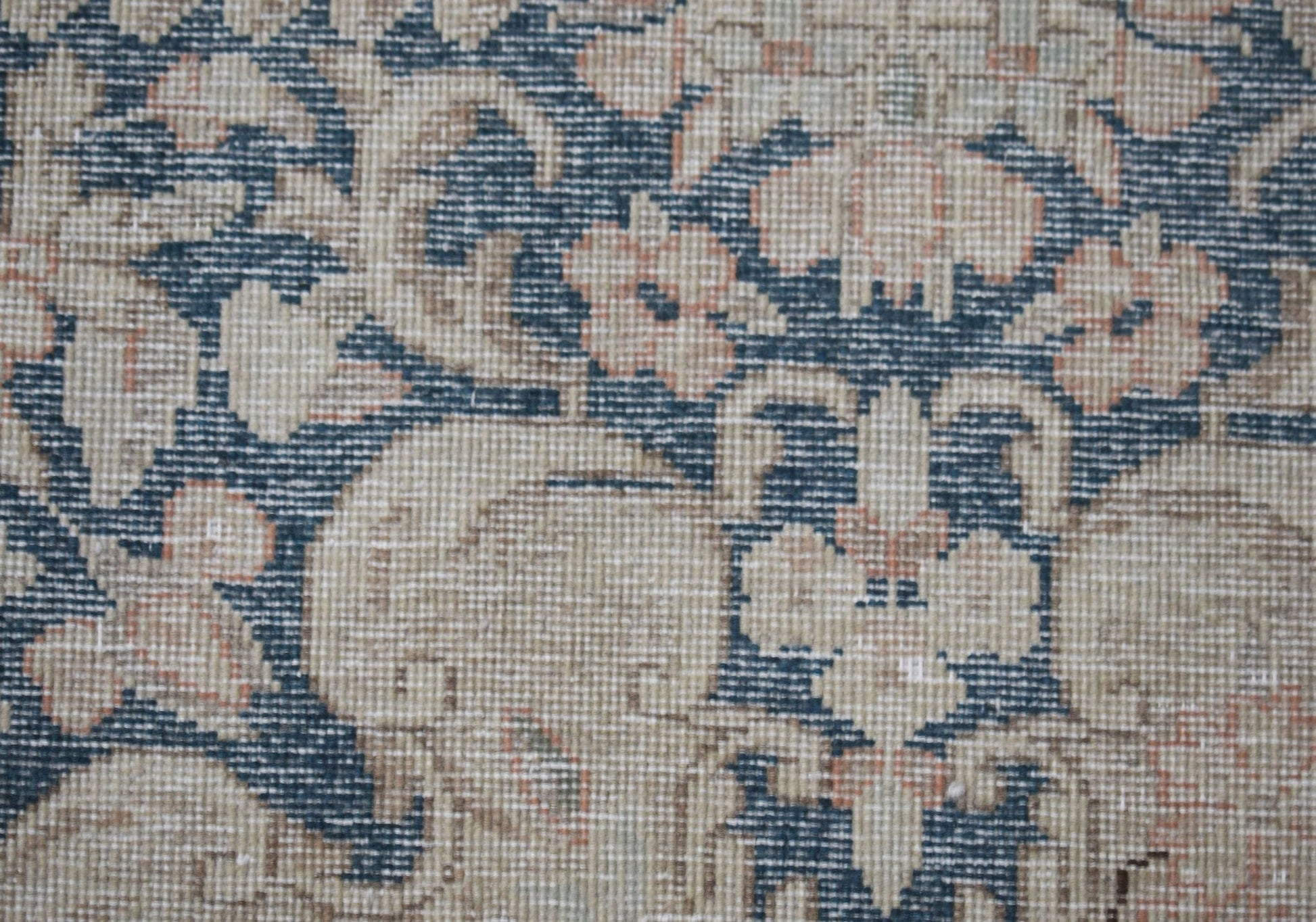 A close-up of a vintage Persian Kerman rug featuring intricate floral patterns in blue and beige.
